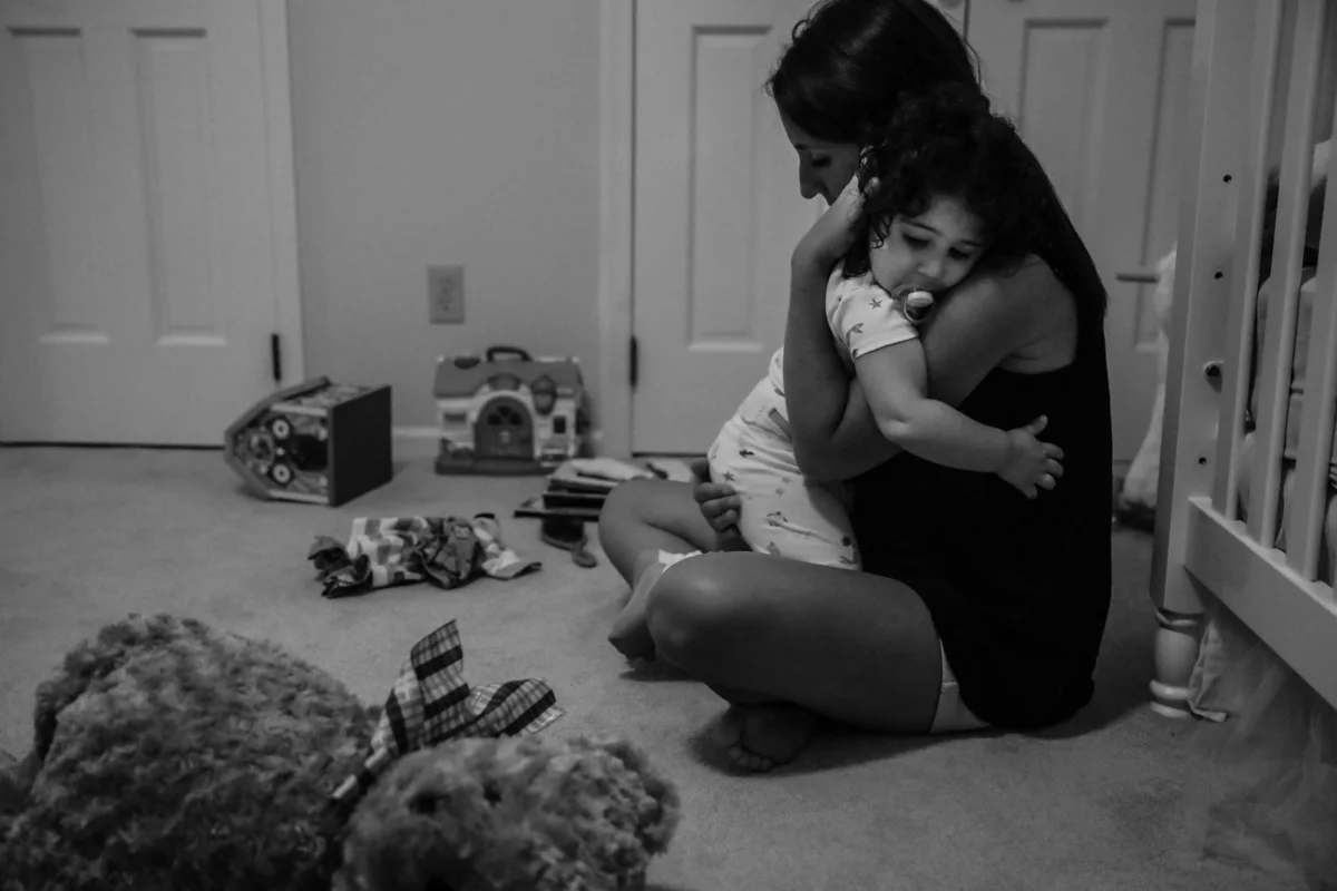 Woman holds tired girl in her arms