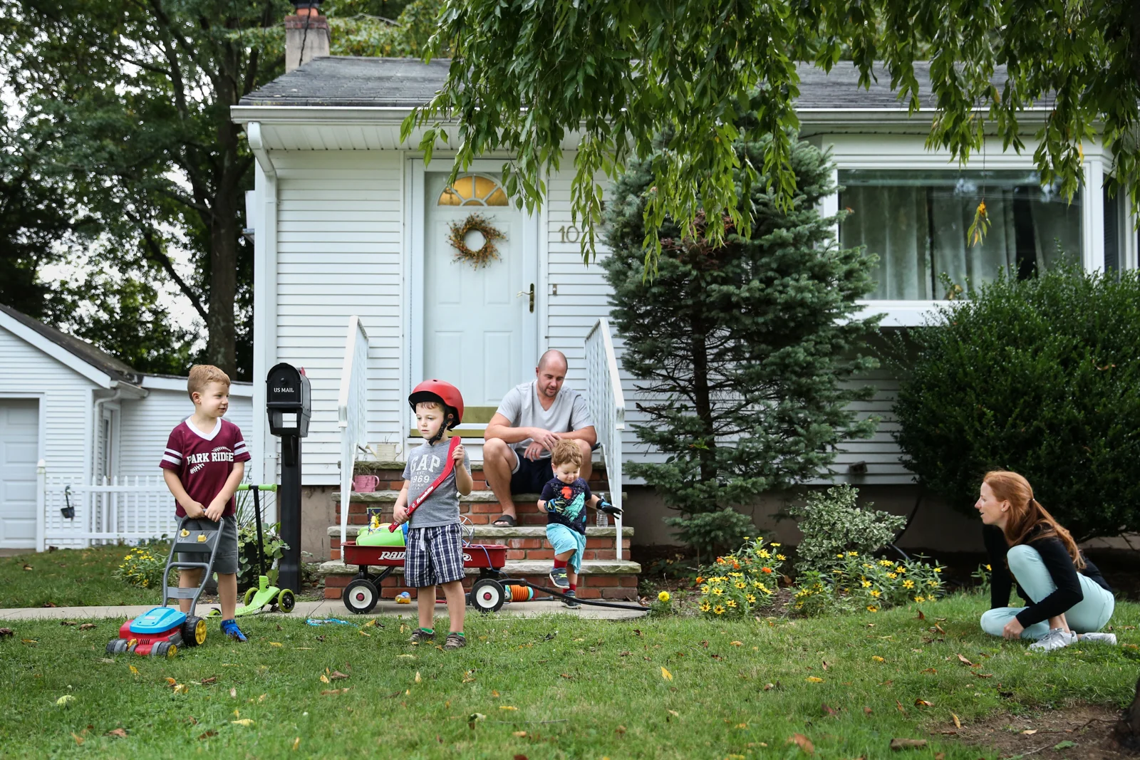 Man, woman, and their 3 sons stand in front of their house
