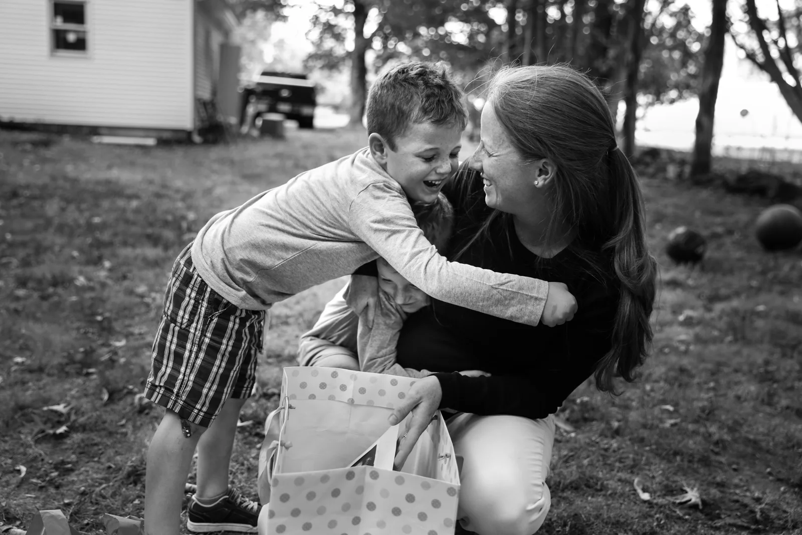 Woman and two boys laugh and hug each other
