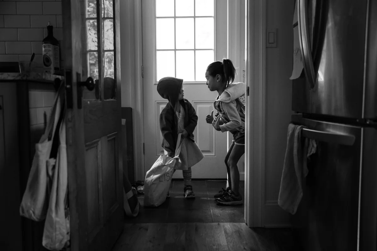 Two girls stand in a doorway with shoes and jackets on
