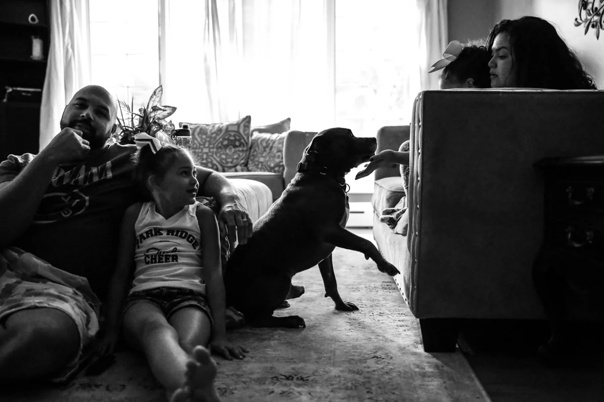 Family of four sit in living room with their dog