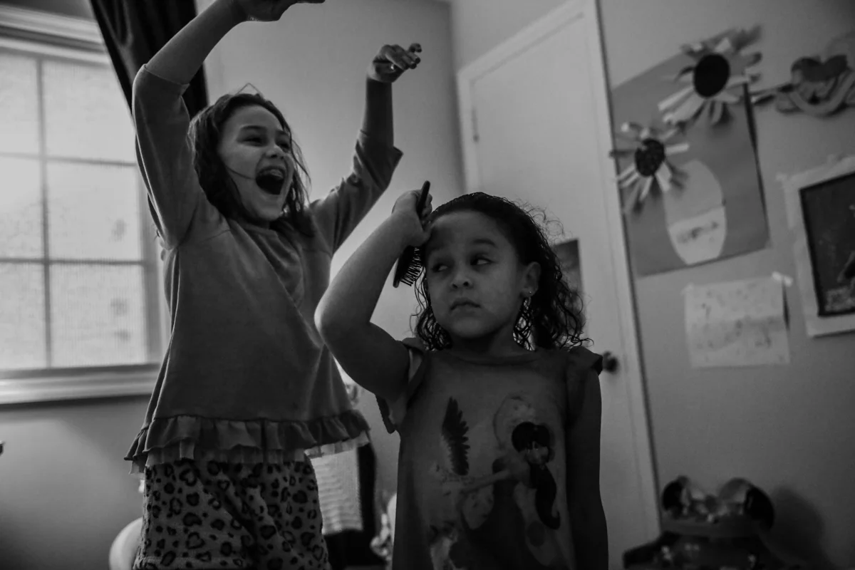 Girl brushes hair, unamused by other girl trying to scare her
