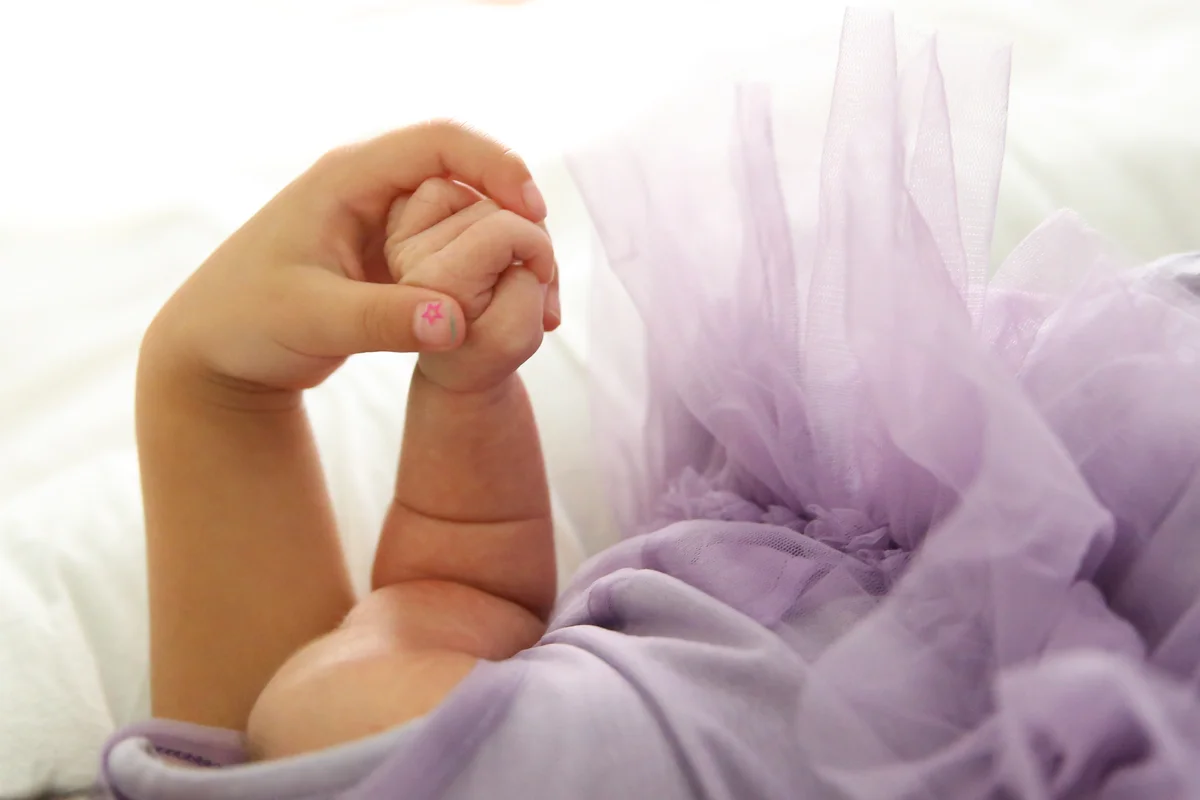 Old child's hand holds baby's hand