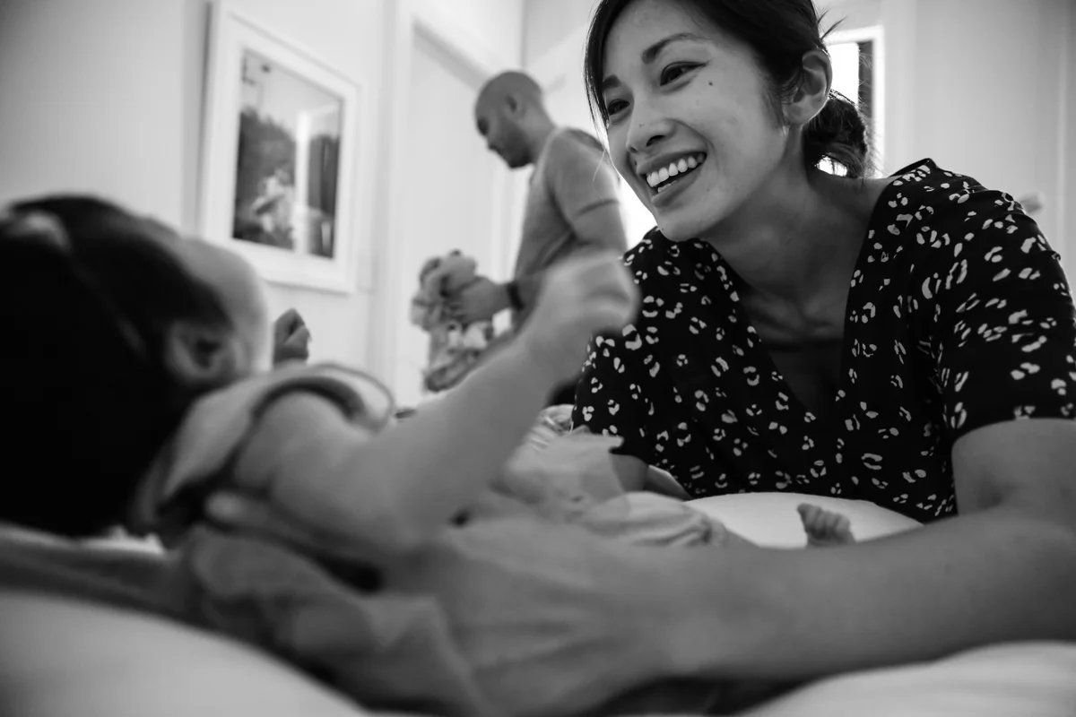 Woman smiles while picking up baby 