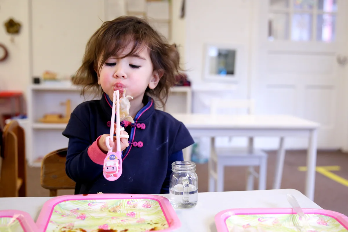 Dumpling hangs off girl's mouth while eating with chopsticks