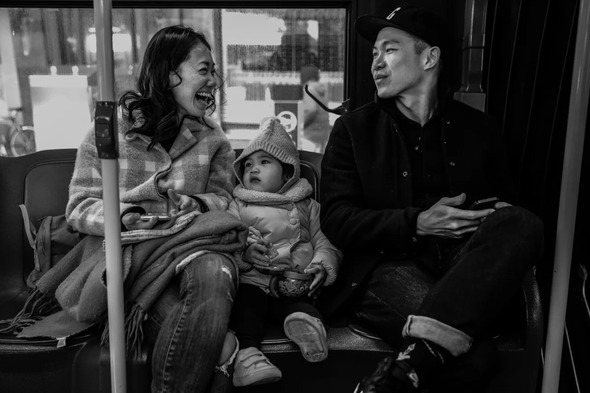 Man and woman smile at each other with girl in middle while sitting on the bus