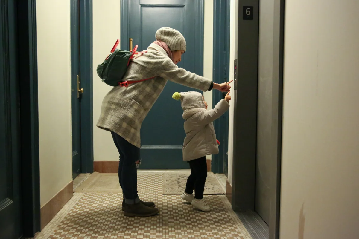 Girl and woman reach for elevator button