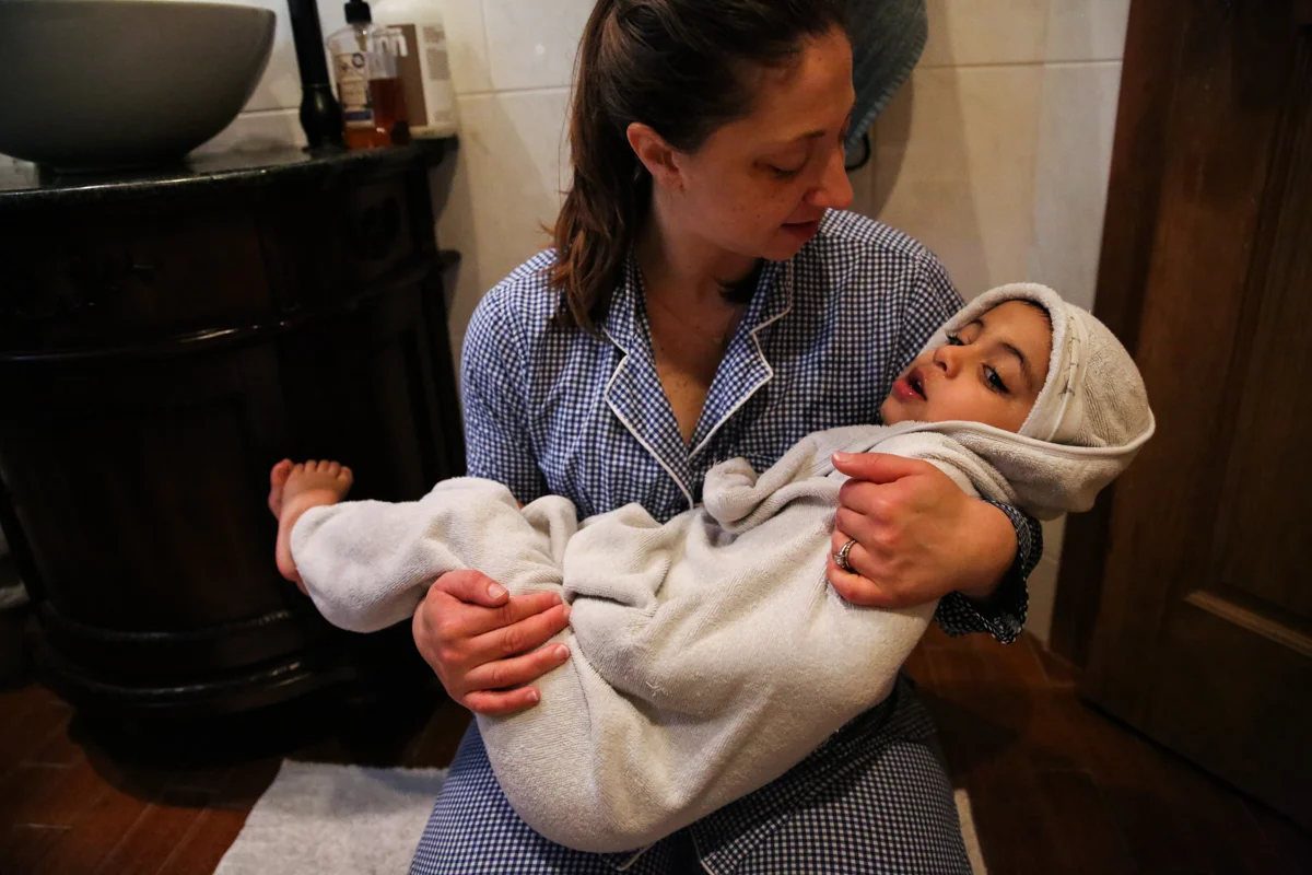 Woman holds child wrapped in towel