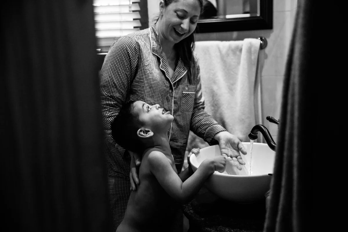 Boy and woman share a smile at bathroom sink