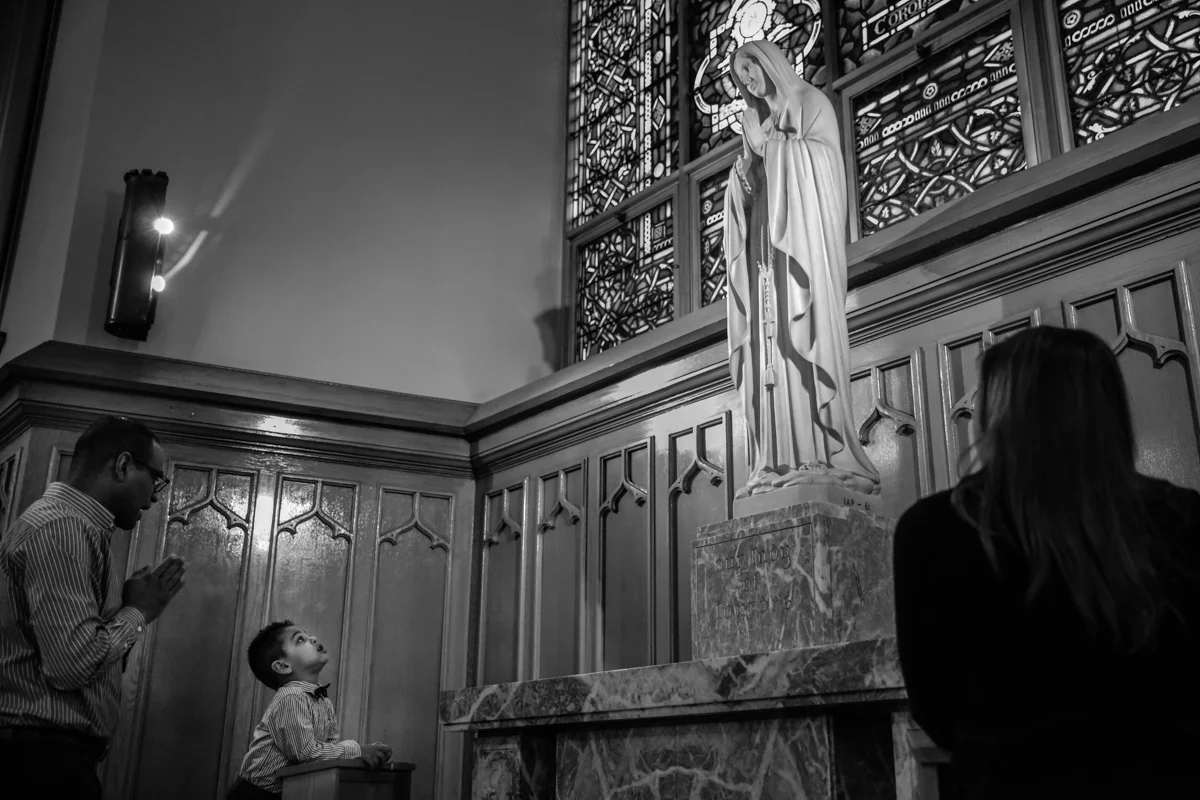 Boy looks up at a statue of Mary
