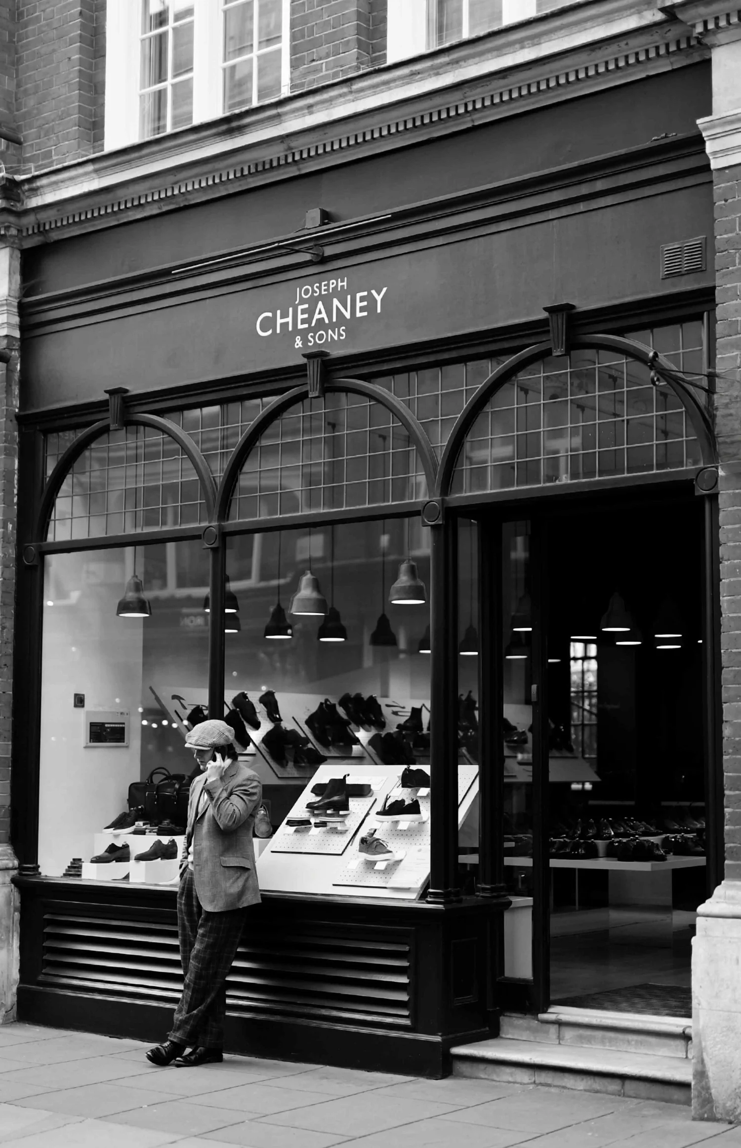 Black and white street photograph of a smartly dressed man outside a shop