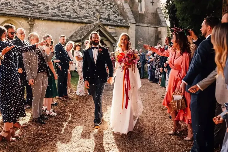 A couple walking through confetti with their guests at Elmore Court