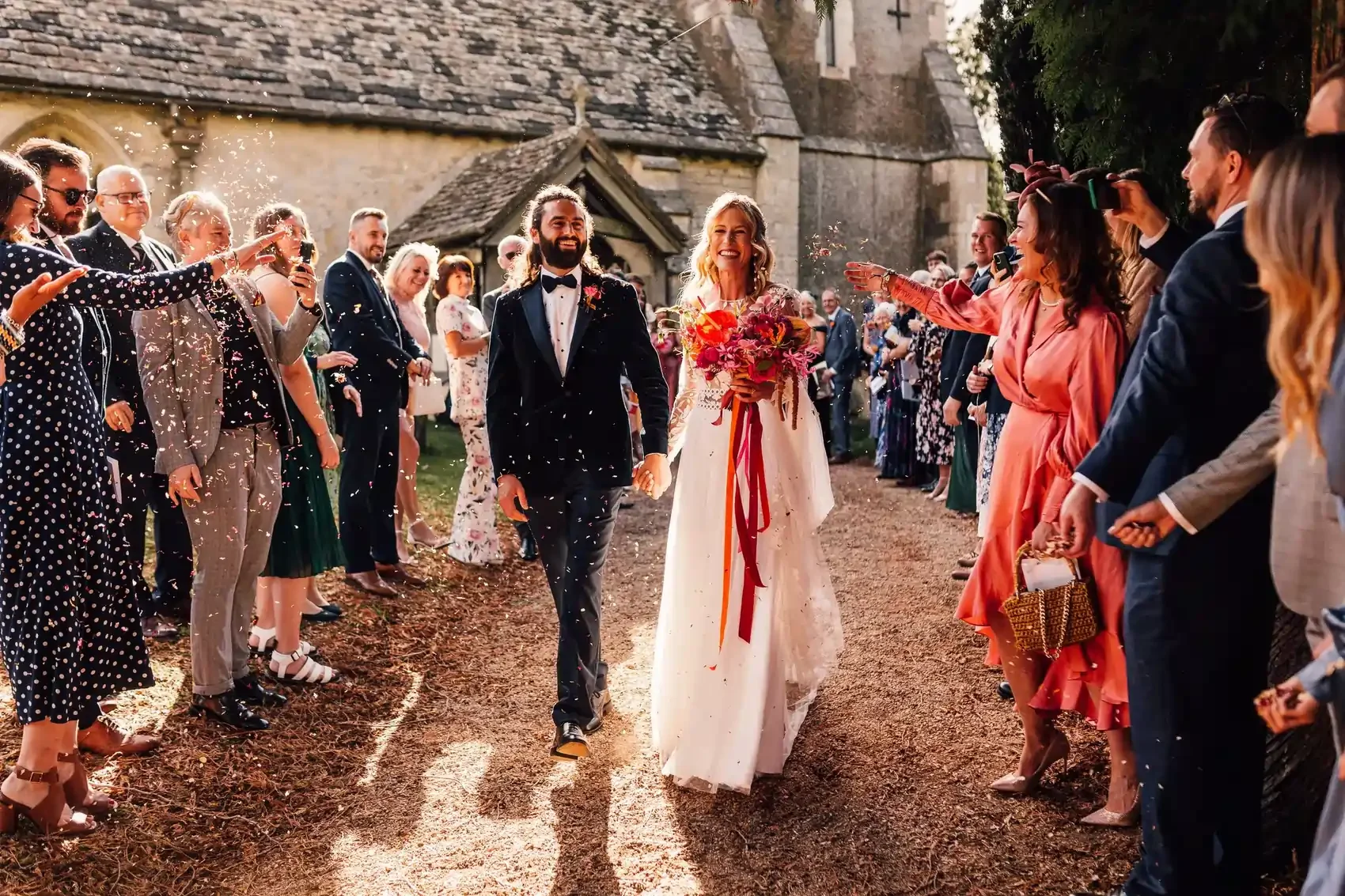 A bride and groom walking through confetti, photographed by Andy Matheson