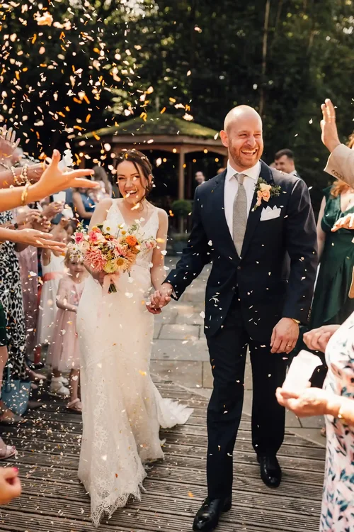 A newly married couple walking through confetti