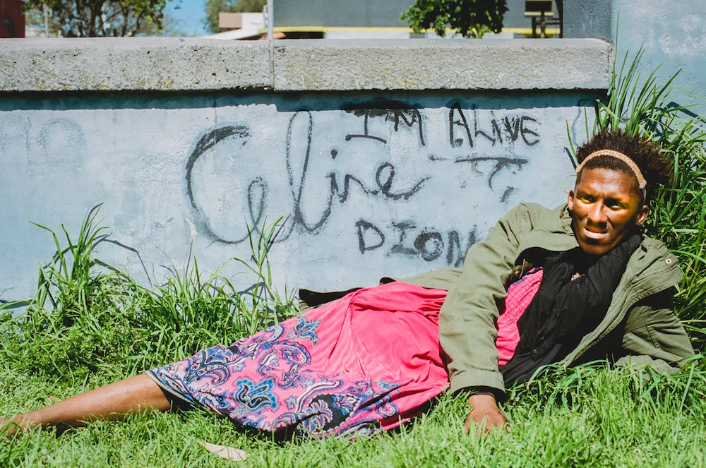 Celine poses for a photo in front of a graffiti affirmation she painted back in 2015 in the park where she stays. Visible only from the interior of the park, this is a personal reminder for herself to keep going even when things are tough.