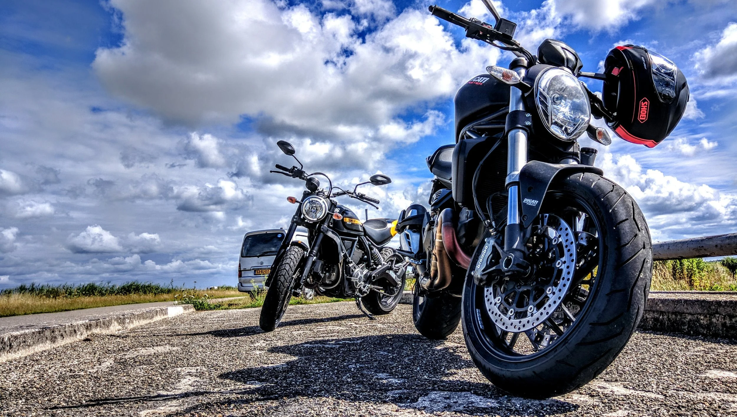 Photograph: Two motorcycles parked against a beautiful blue sky with dramatic clouds.