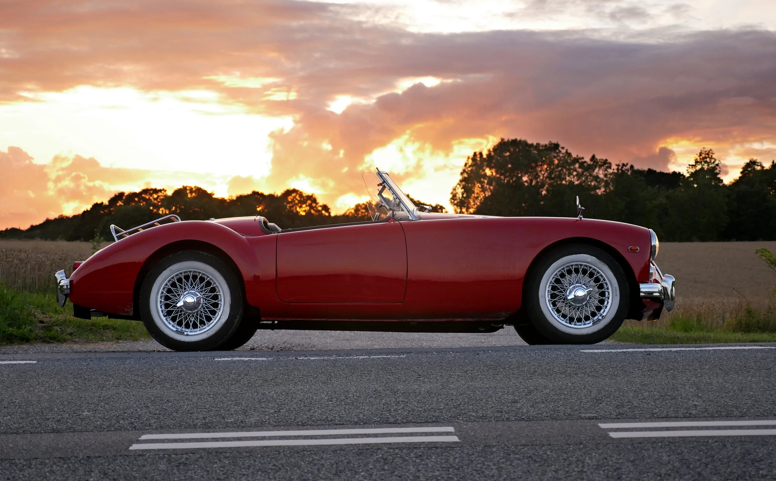 Photograph: Beautiful restored red MGA sports car against a dramatic orange sunset.