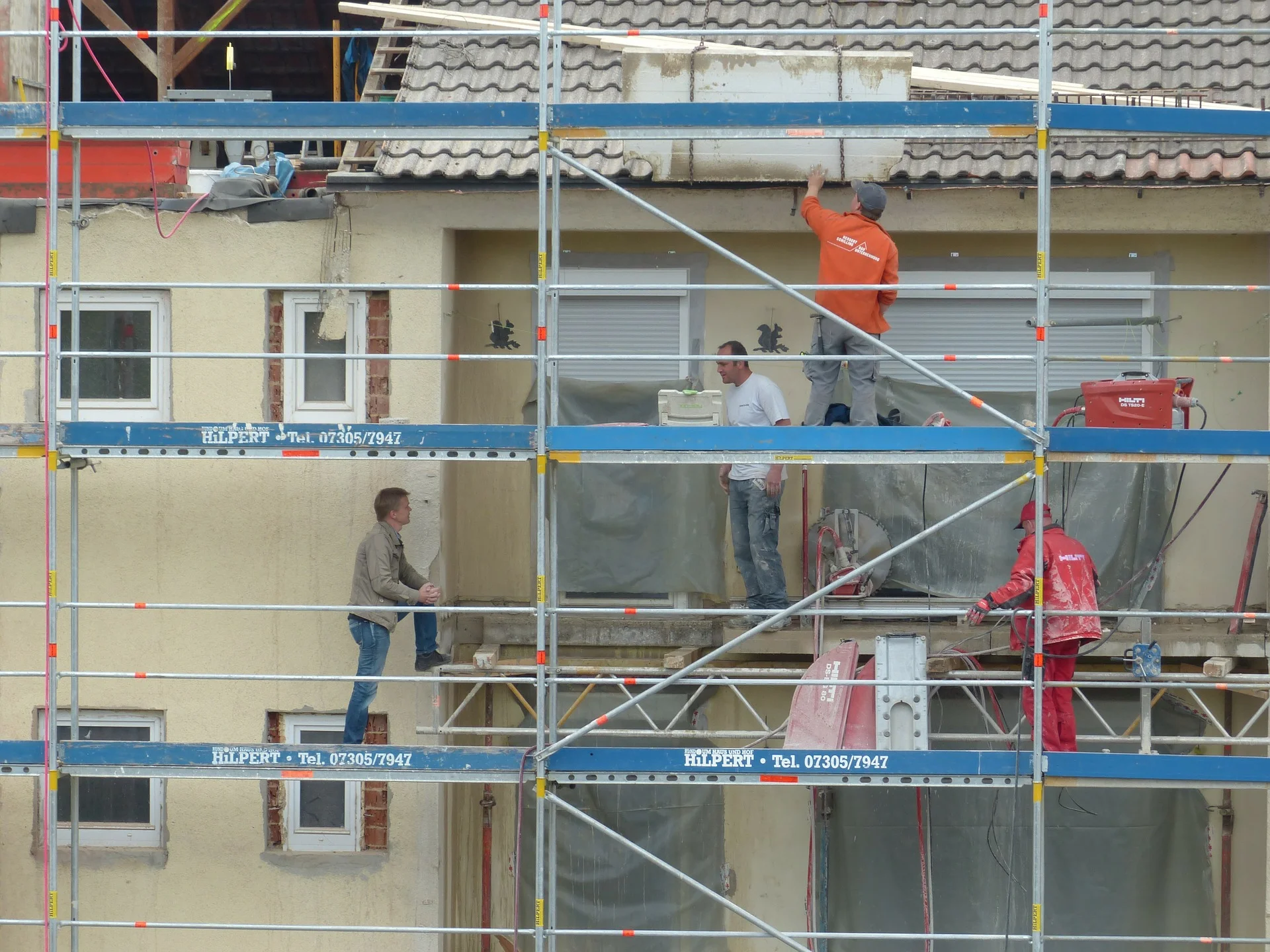 Photograph: Workings standing and climbing on scaffolding at a worksite.