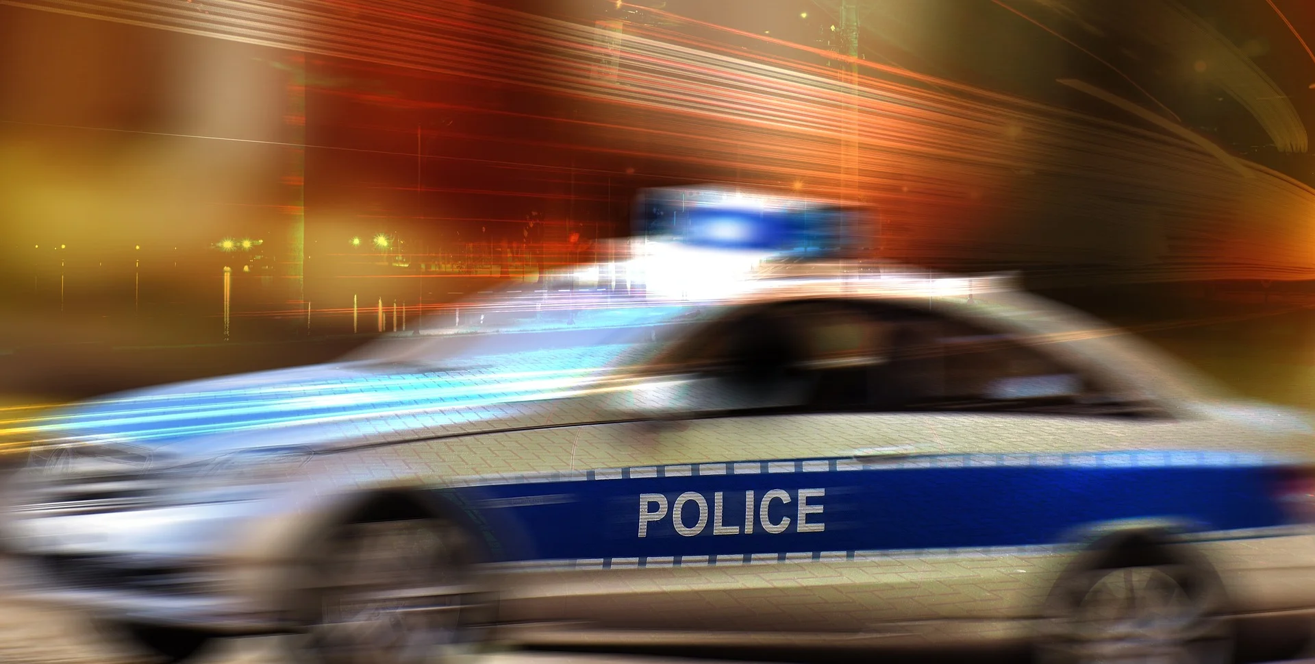 Photograph: Speeding police car in a blur with its emergency lights on.