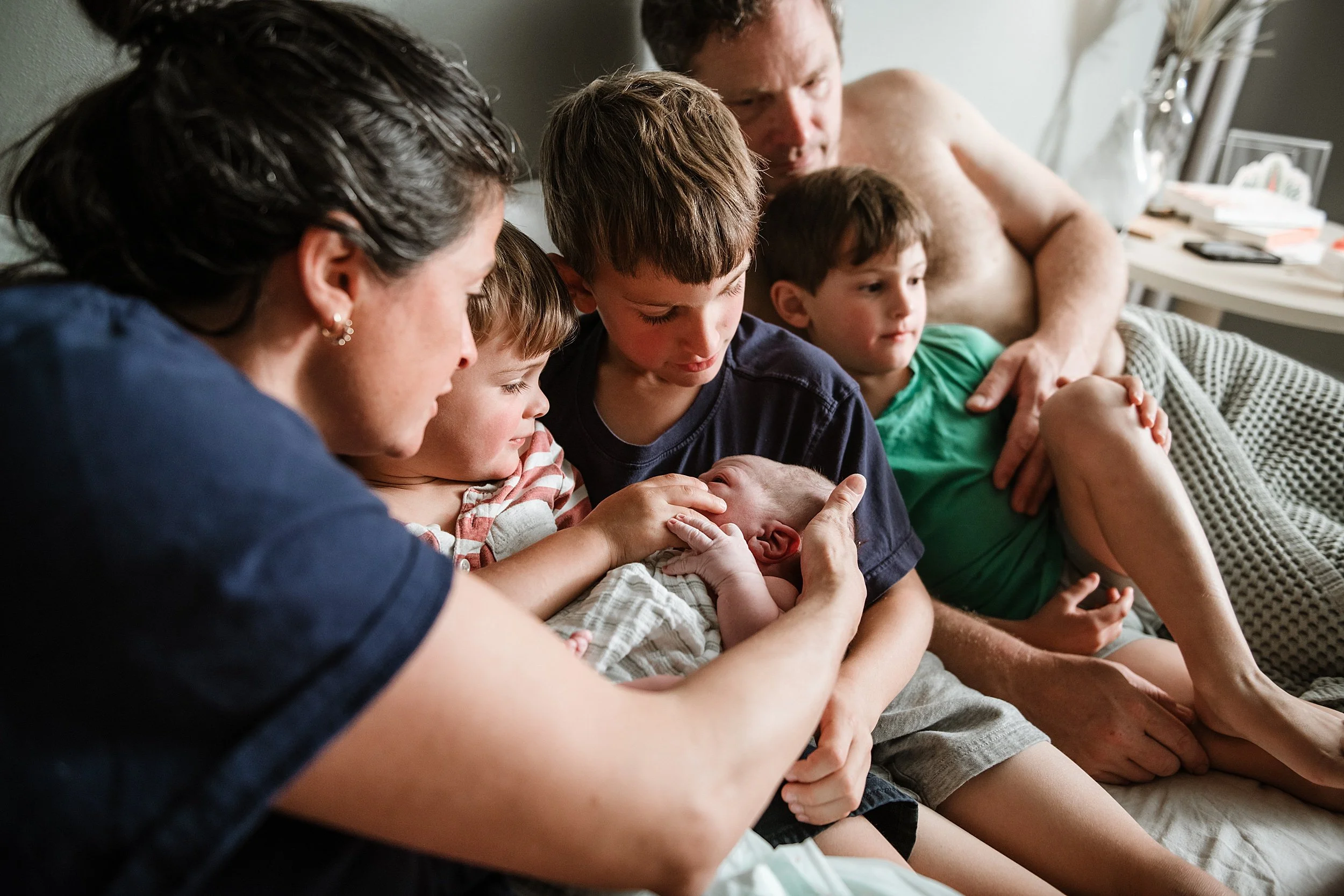 Mother and children looking at new baby after birth at home