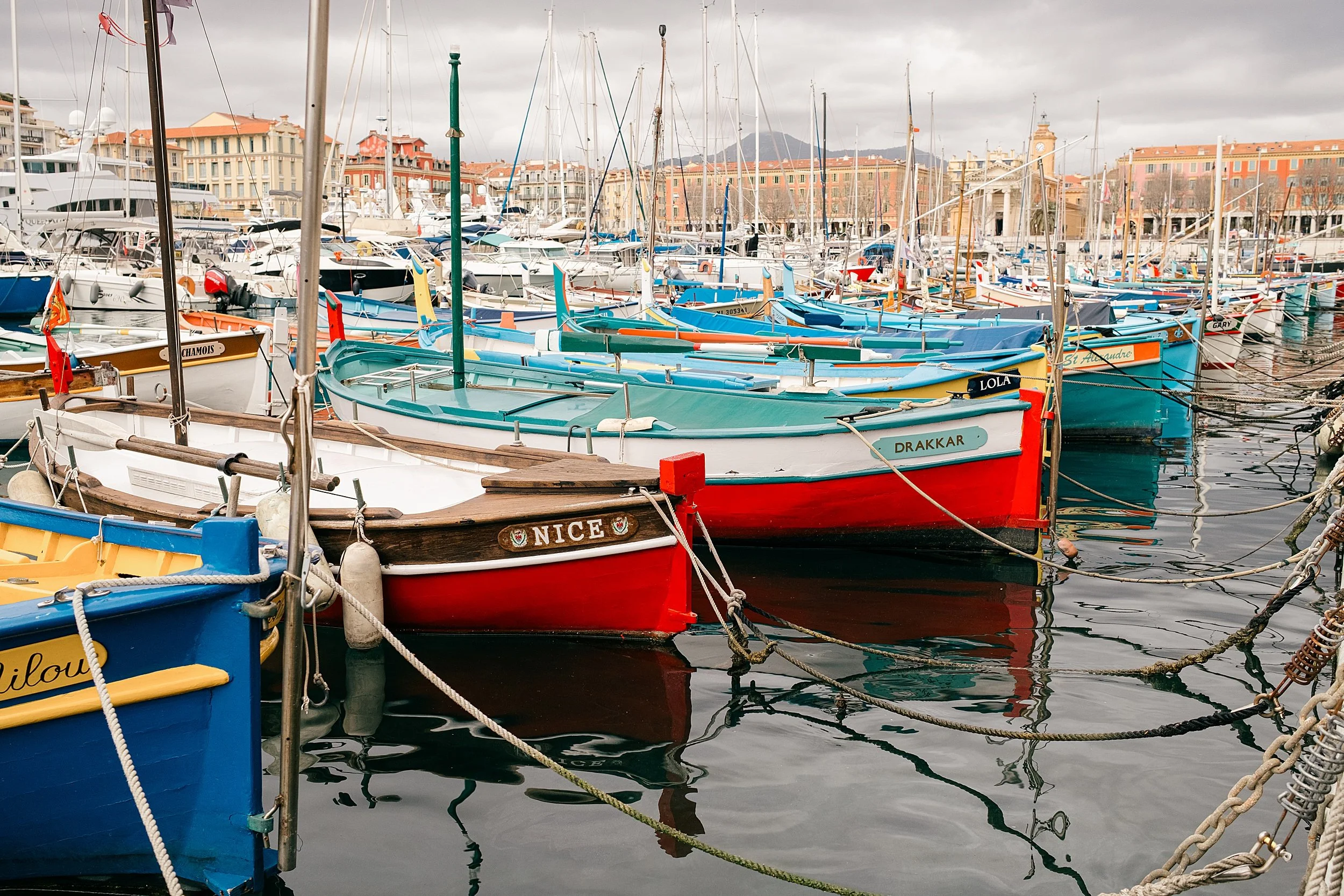 Traditional fishing boats and modern vessels create a timeless maritime scene in Port Lympia, Nice, France