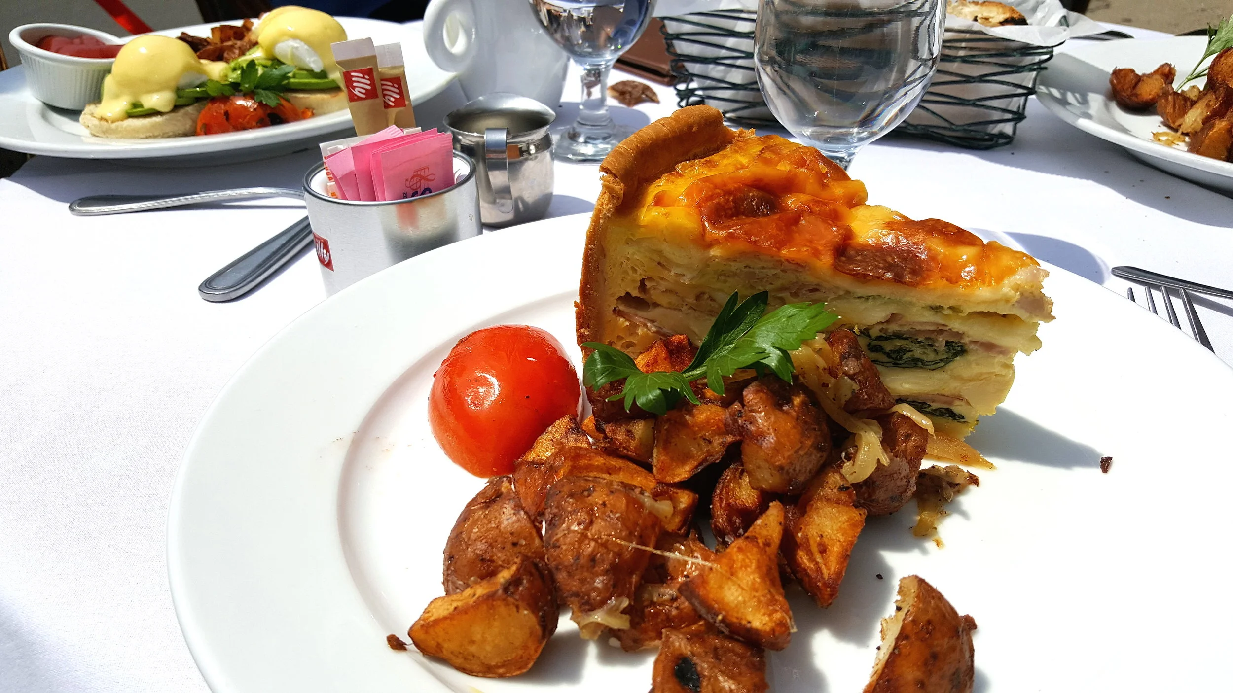 Homemade quiche, country ham, cheese, spinach, and home fries (front) and eggs Benedict, Canadian bacon, hollandaise, and home fries (back).