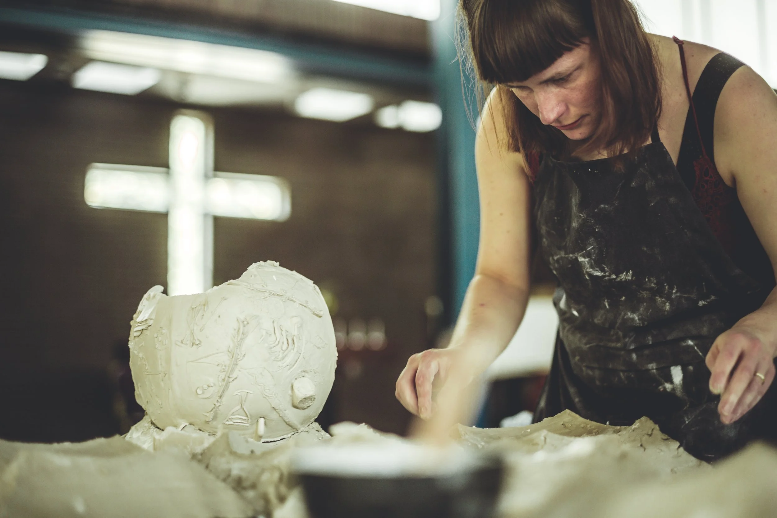 An image of a female potter making a clay Easter egg in the main church hall.