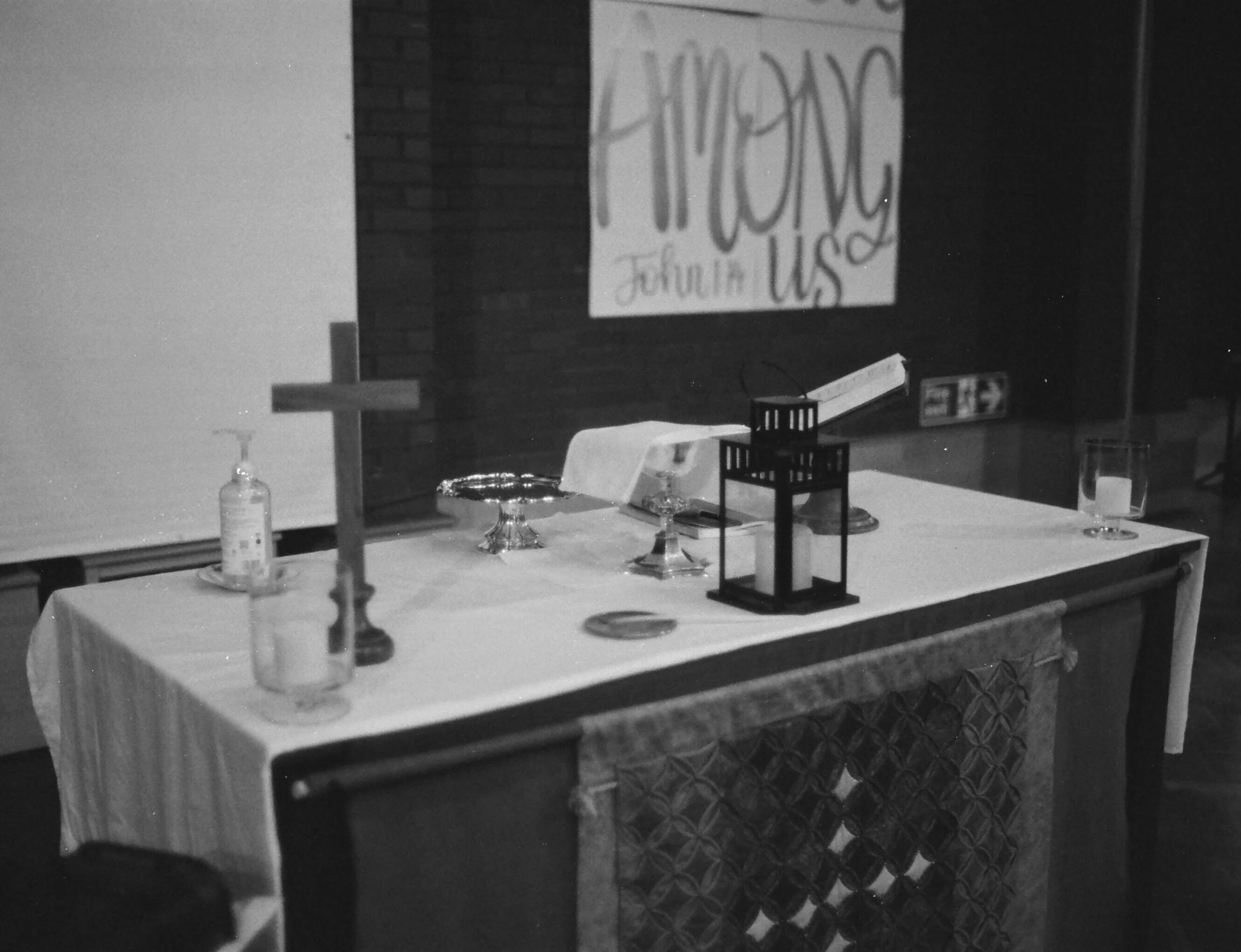 A photo of St. George's altar captured on film camera. The altar has a candle, communion silver, cross, and missal on it.