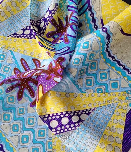 Close-up of a colourful fabric with an intricate pattern in shades of yellow, blue, purple, and brown.