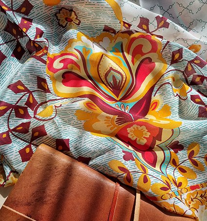 Close-up of 'Comillas' scarf with a leather-bound notebook in the corner.