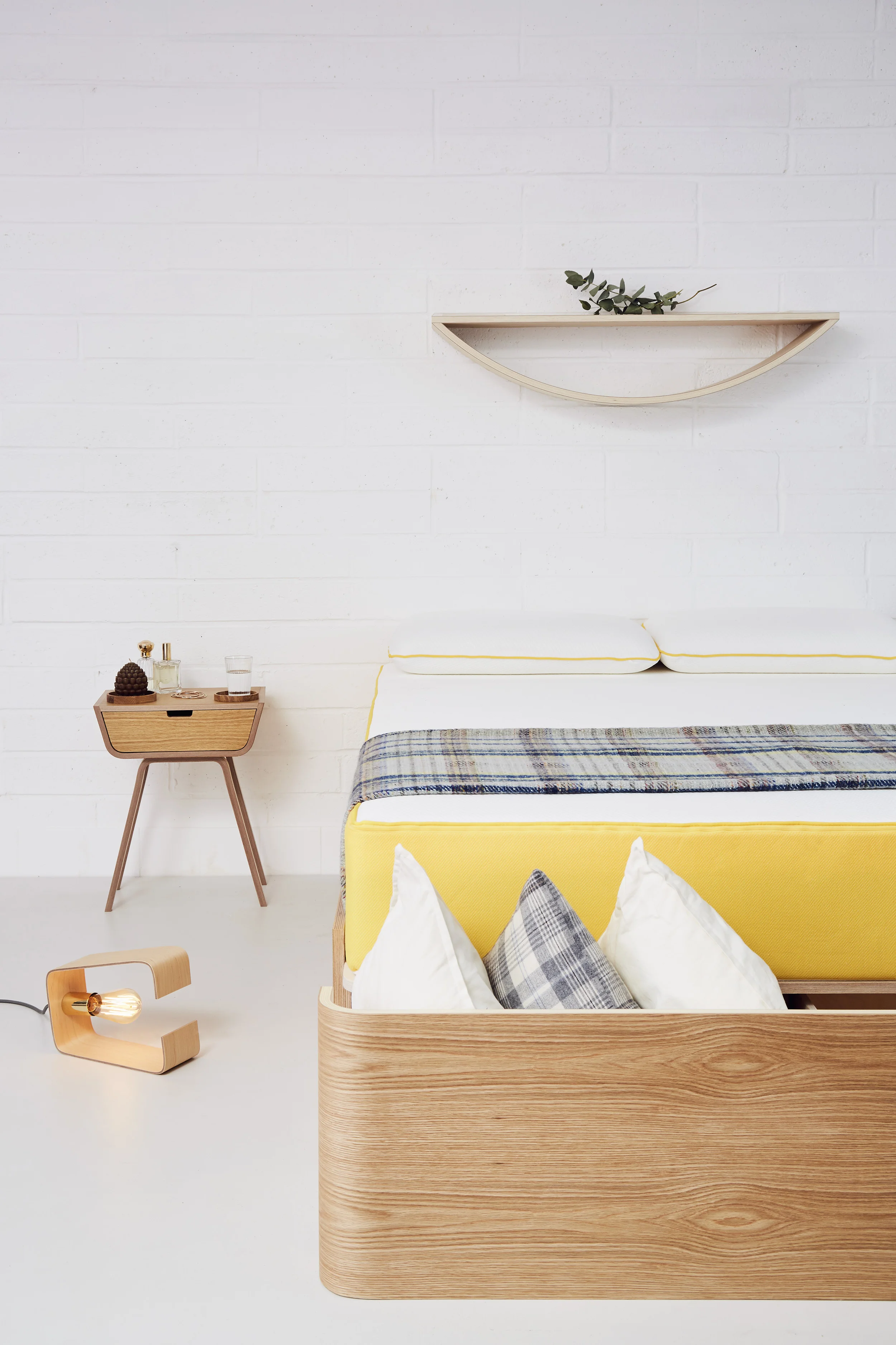 Curved plywood bed frame by Lozi, with storage drawer and bedside table.