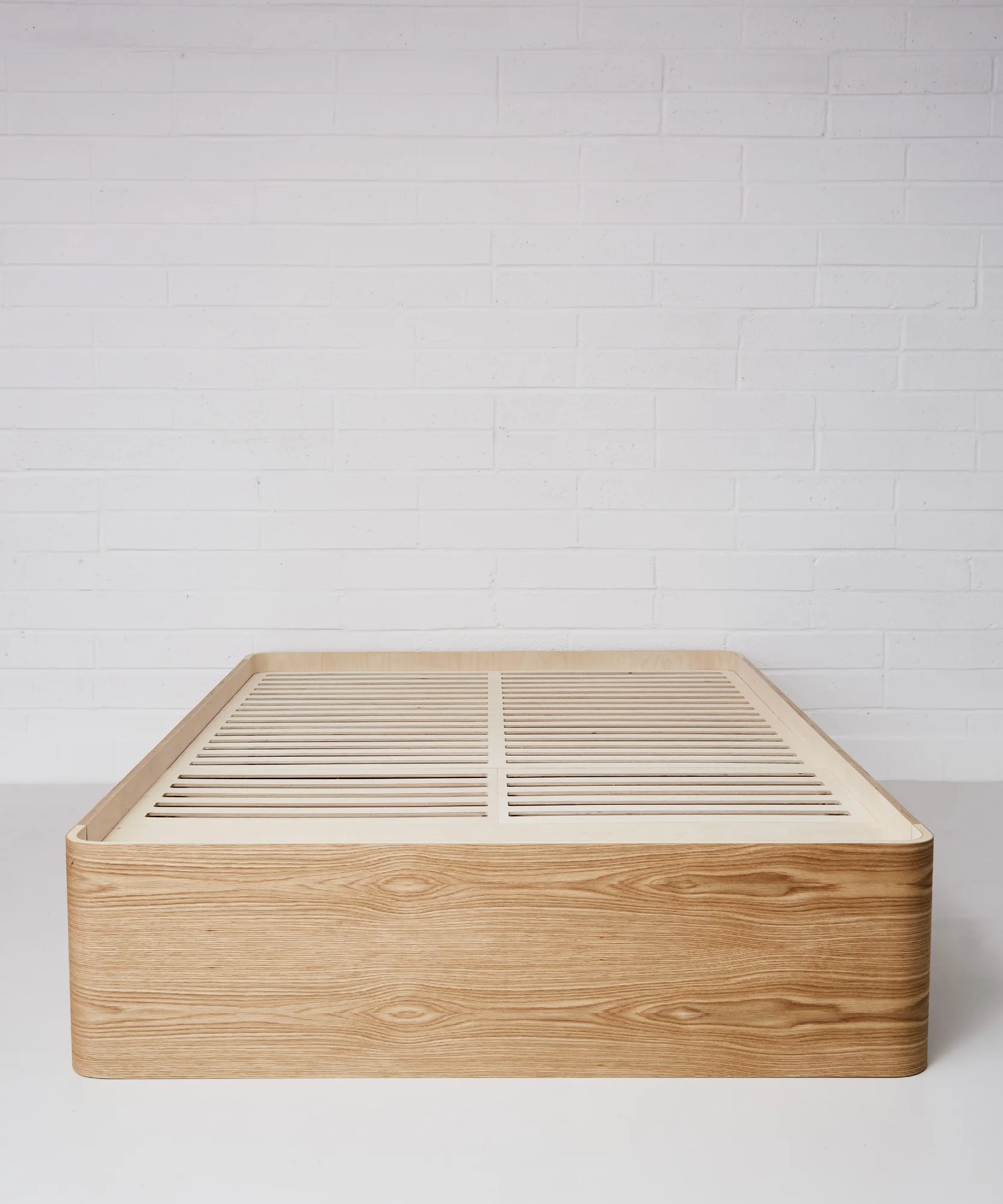Curved plywood bed frame by Lozi, with storage drawer.