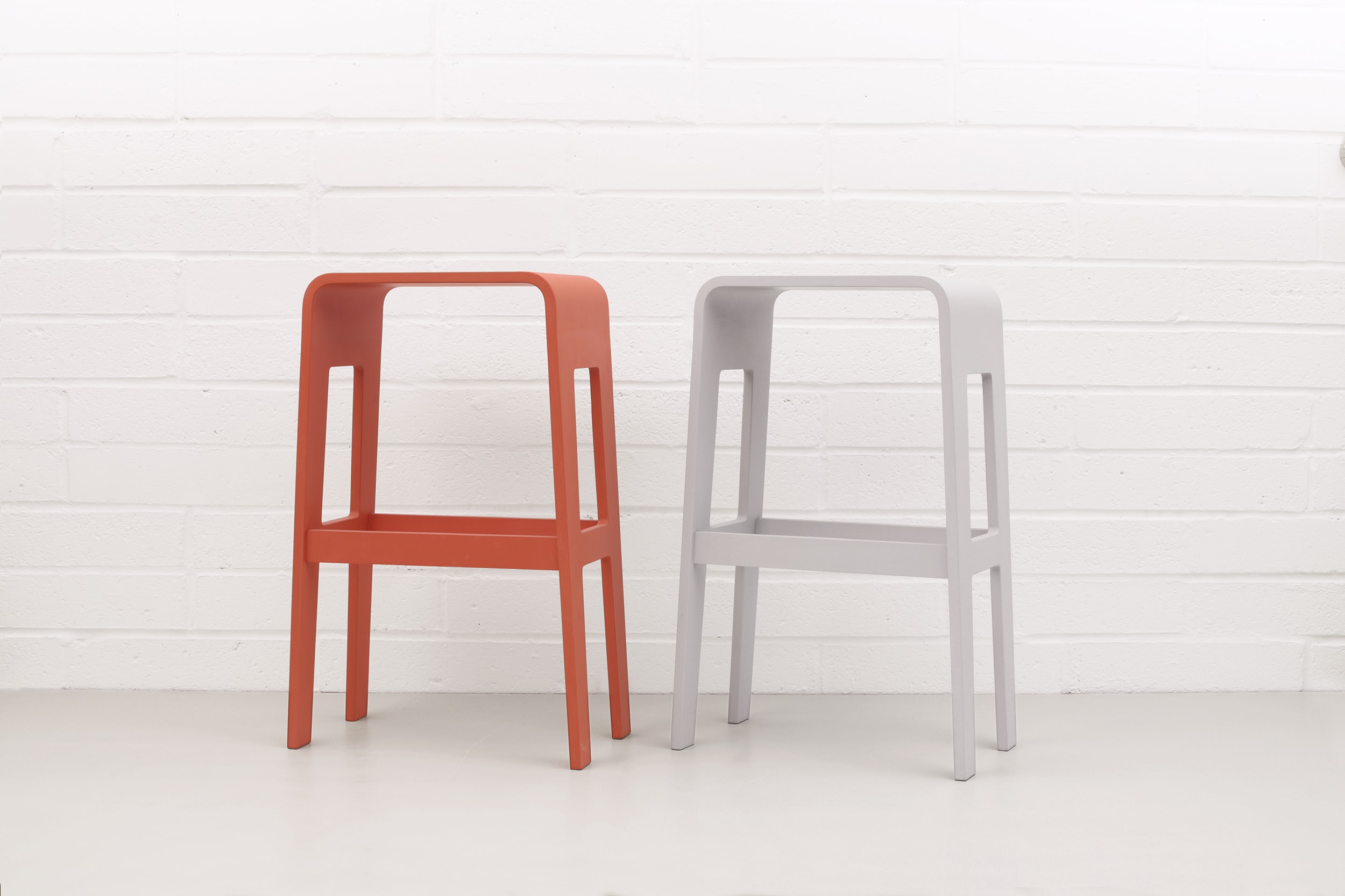 A pair of curved plywood barstools by Lozi painted Orange and Seagull Grey