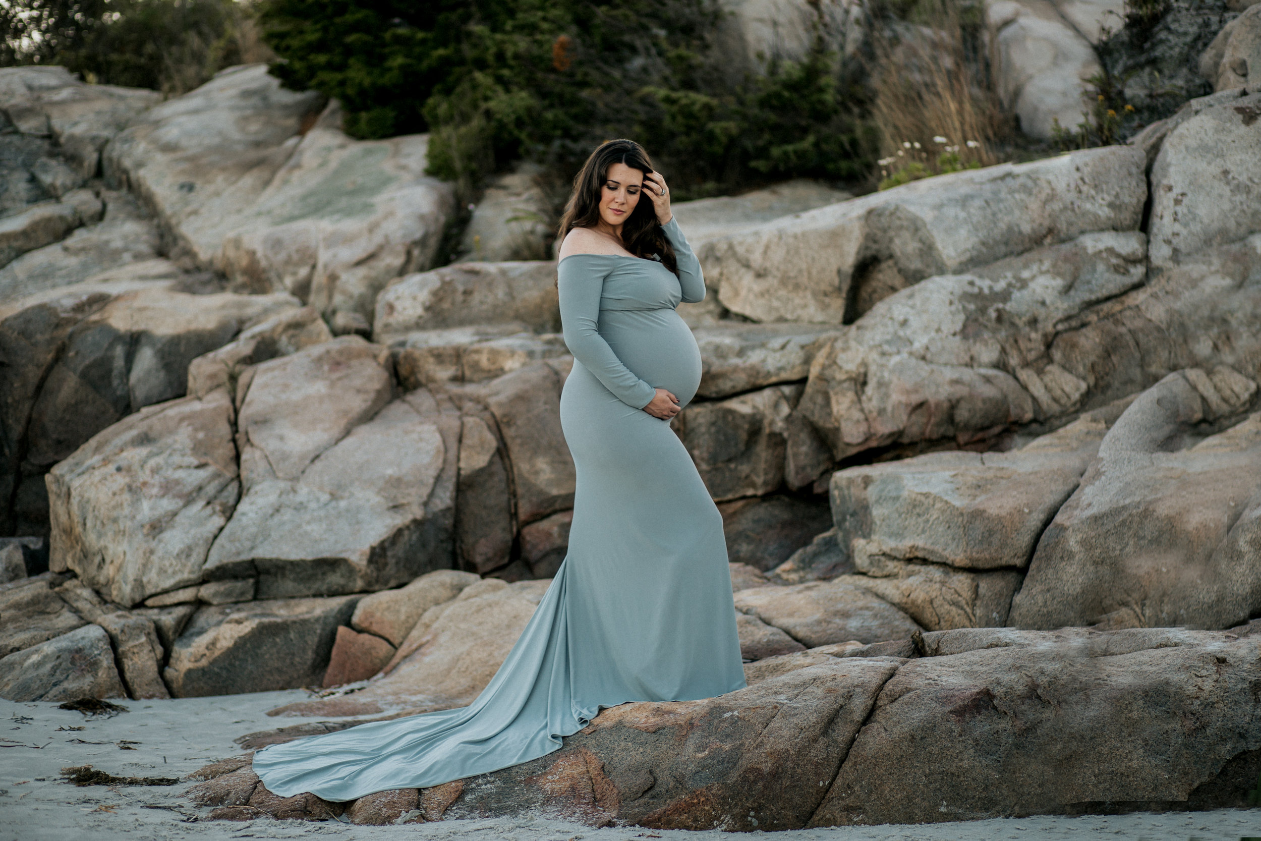 beach session with expectiong mom during maternity session with rocks on background