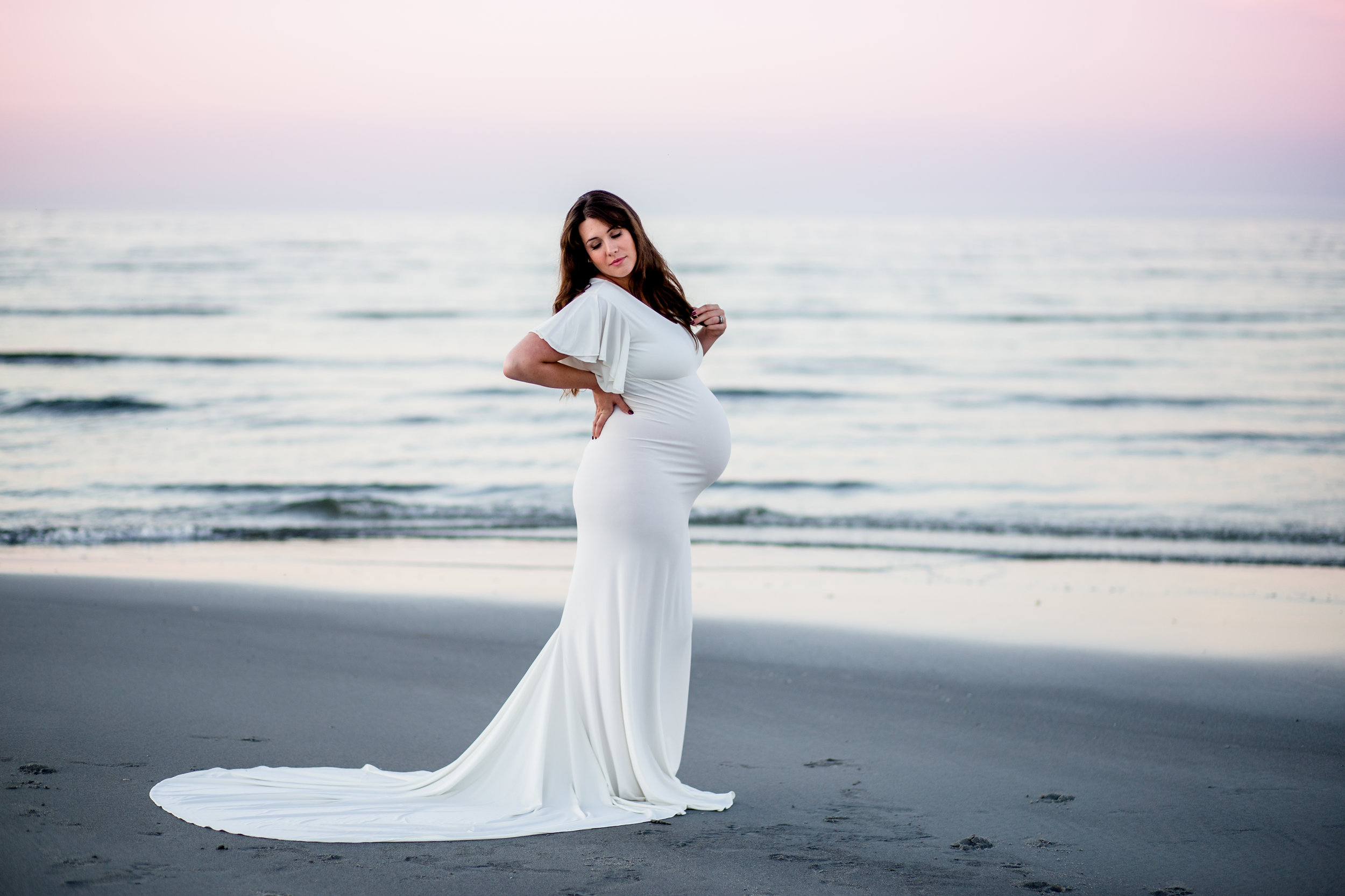 beach maternity session with colorful sky and designer dress