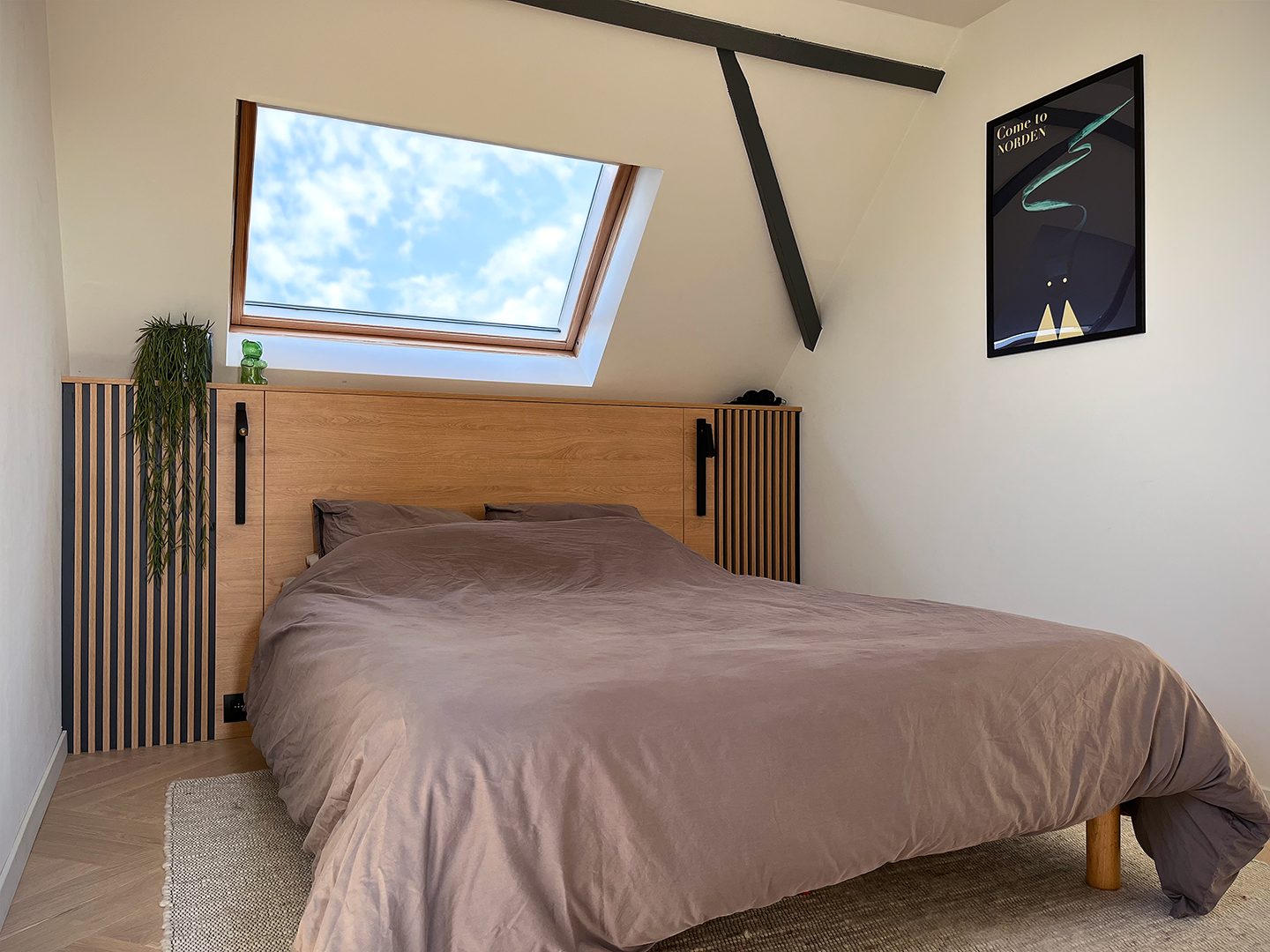Tête de lit en bois effet claustra installée sous le versant de toit pour délimiter l'espace nuit parental.