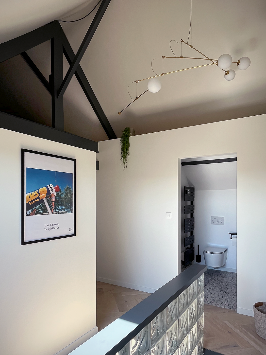 Grand luminaire suspendu effet mobile accentuant la verticalité sous toiture près de la mezzanine de stockage