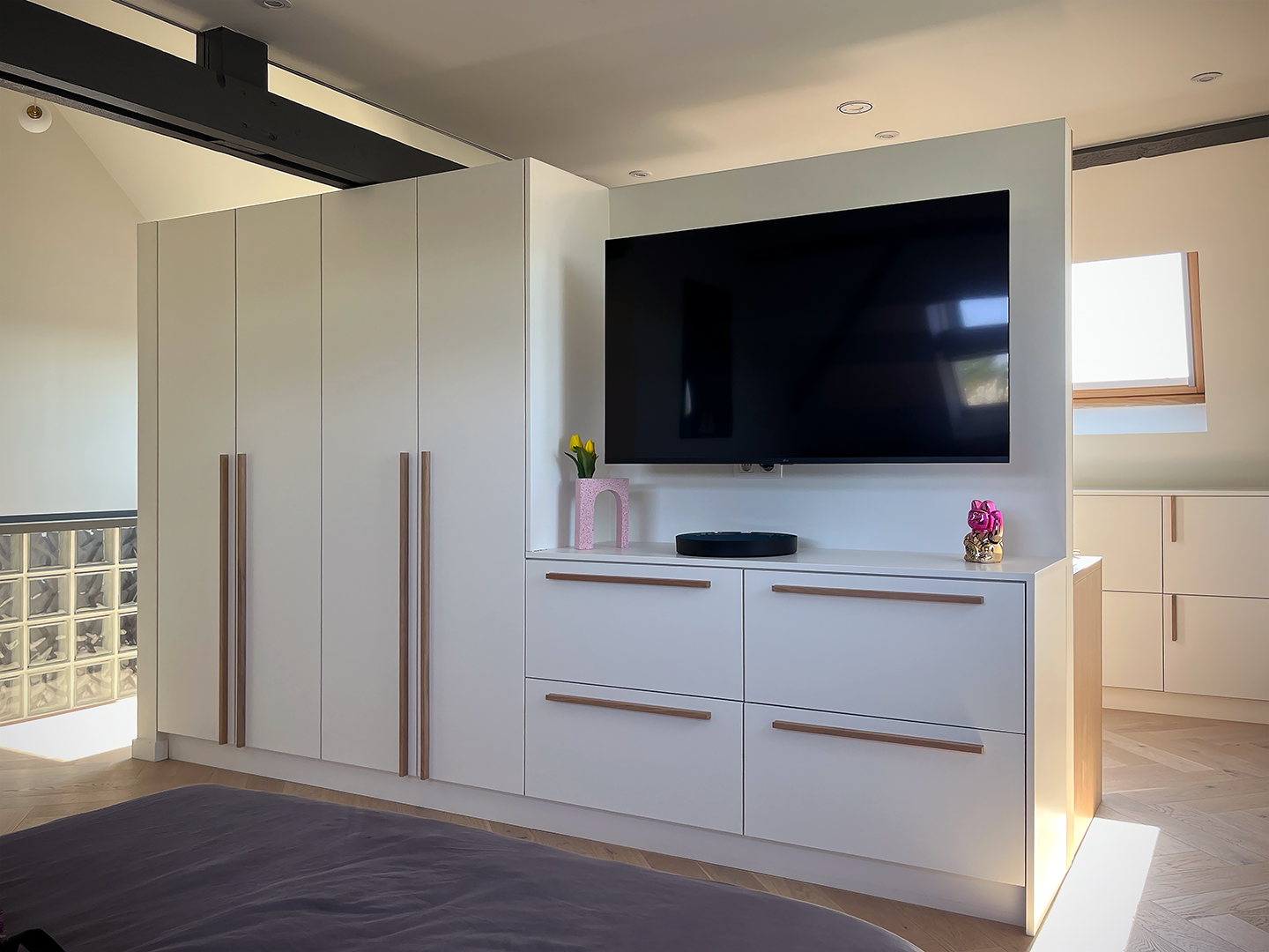 Agencement de meuble TV et dressing blanc et bois sur mesure dessiné en alignement avec l'espace lit sous pente