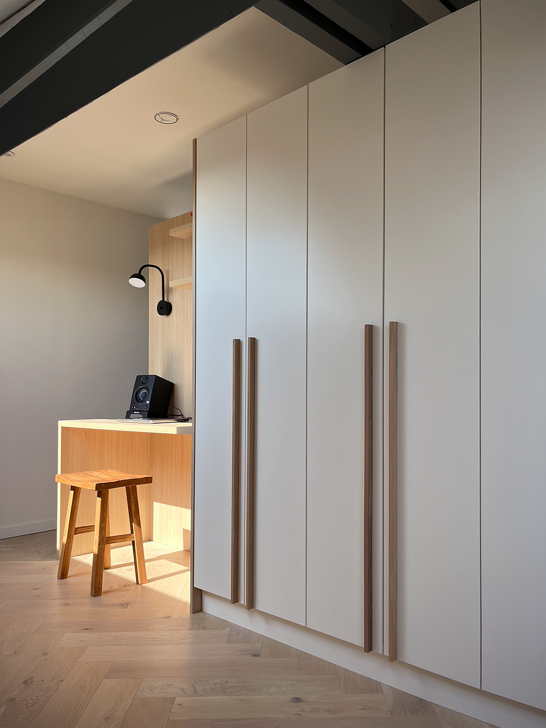 Aménagement d'un petit coin bureau fonctionnel en bois clair adossé au bloc de rangement sous les combles