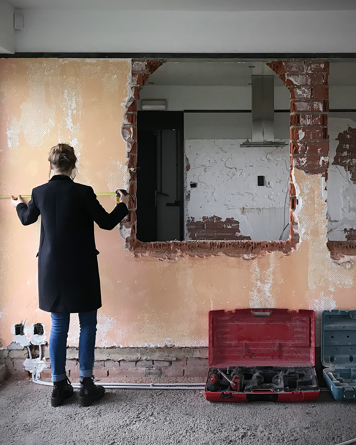 Person measuring a wall with a tape measure during remodeling or construction work