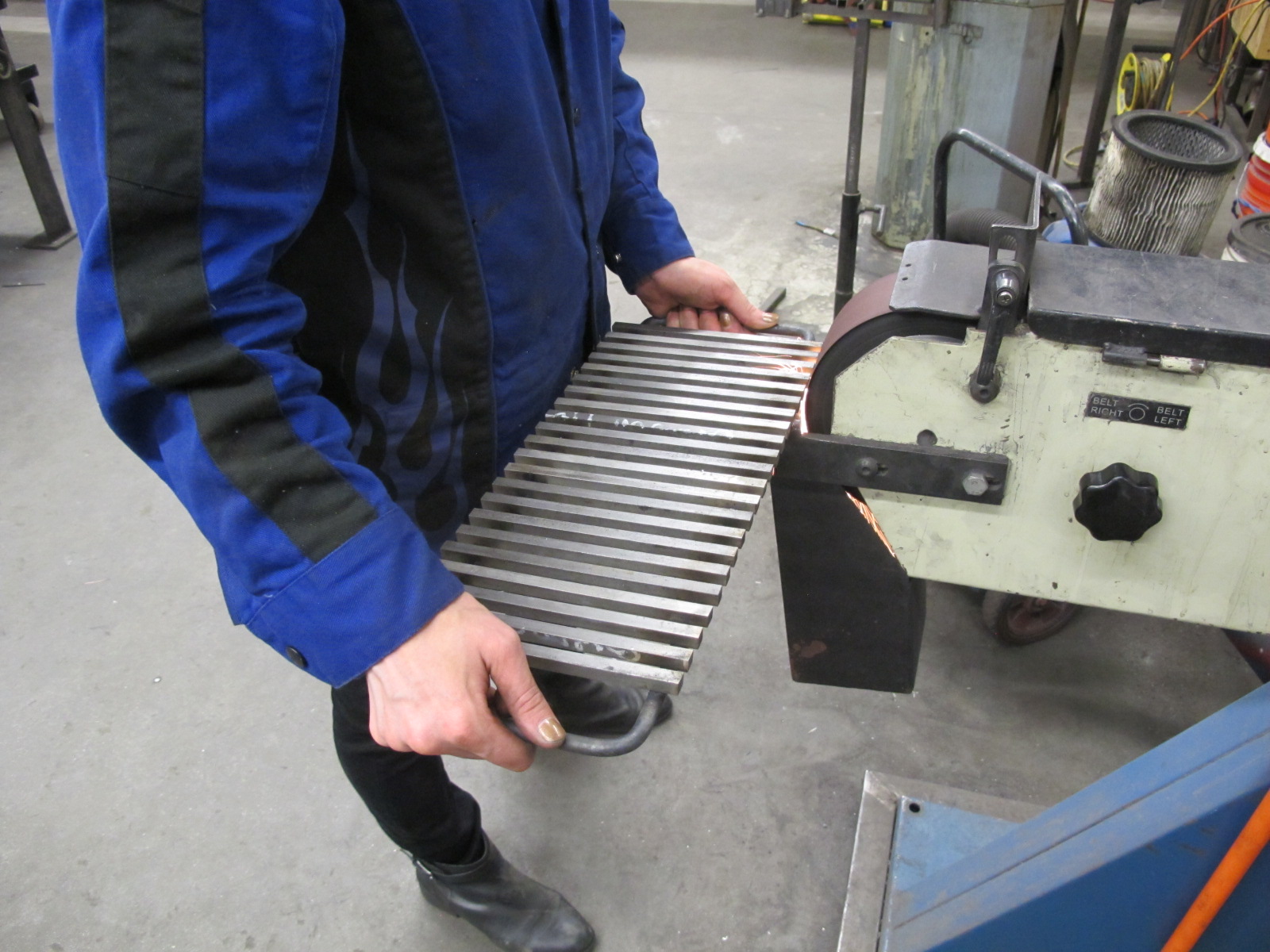  Student grinding part on a belt grinder 
