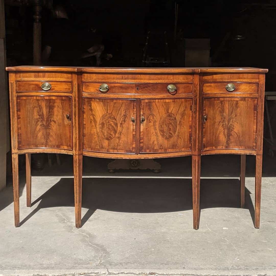 Here we have a beautiful federal style sideboard circa early 19th century.

We did some repair to the legs and an overall touch-up.

As some of you may notice, these sideboards are well known for the delamination of the curved doors where the crotchw
