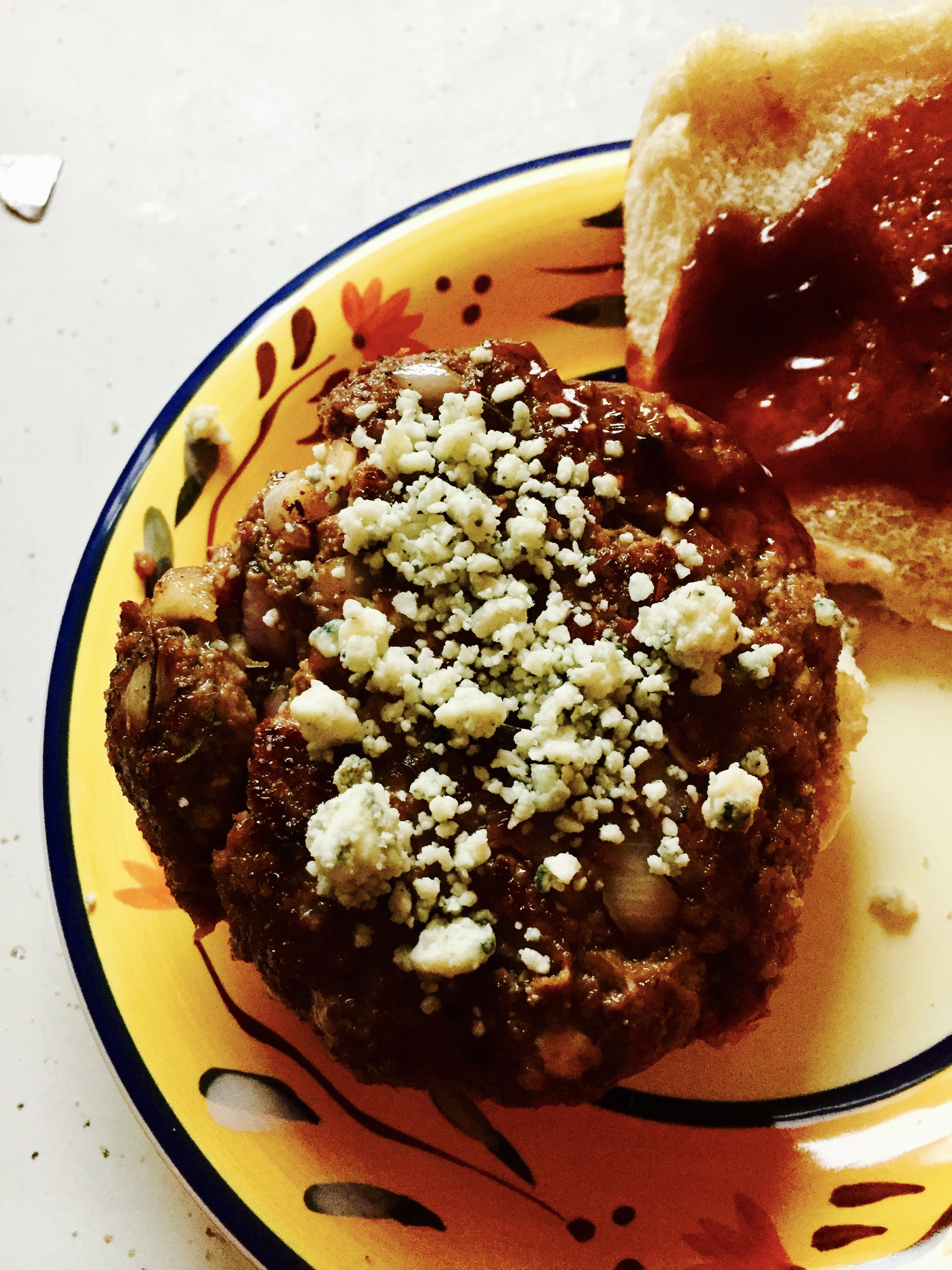 Ingredients Lb of Ground Beef Shallot garlic powder Rosemary Bleu Cheese Crumbles (cup) 3 tbls of barbecue sauce 2 tbs of soy sauce crushed black pepper Seasoned bread crumbs (2 tbls) Dice the shallots (amount according to preference...I used about a nickel sized amount of diced shallot per burger)* I call it putting my 5 cents in...get it? Yeah, I know ya do)... Add ground beef, shallots, barbecue sauce, soy sauce, garlic, seasoned bread crumbs to a medium sized bowl. Mix your beef with your hands. Remove leaves from the sprig of Rosemary and dice them. Add the Rosemary to the mixture, distributing evenly. Add crushed pepper (according to your preference). In batches, sprinkle some Bleu cheese crumbles and using your hands fold them in to the mixture; add some more and then fold them in. The idea is to equally distribute the crumbles throughout the meat mixture. Keep some of the Bleu cheese to the side to be used to sprinkle on top of the burger when they're served. Grill or pan fry your burgers to your desired degree of wellness. Serve on a bun sprinkled with Bleu Cheese dressing and with your favorite barbecue sauce in lieu of ketchup. * Makes 3 big burgers; 5-6 sm burgers. My comments: AWESOME! Because of the cheese there is a need for serious cooking but it makes for a juicy burger. I didn't have time to put this recipe on the grill but I would definitely be interested in putting them on the grill with this same recipe. I think the product would be actually better. As it was I cooked my burger in a medium skillet and I missed my preferred fire-kissed burger coating ya can only get from the grill. Some people might be inclined to added diced garlic, and this is an option I would also consider. I didn't add my usual egg to this recipe, but I honestly think this would also be something to try. Perhaps this is not the healthiest thing on the menu, but everybody deserves a decadent burger every so often...some more than others...