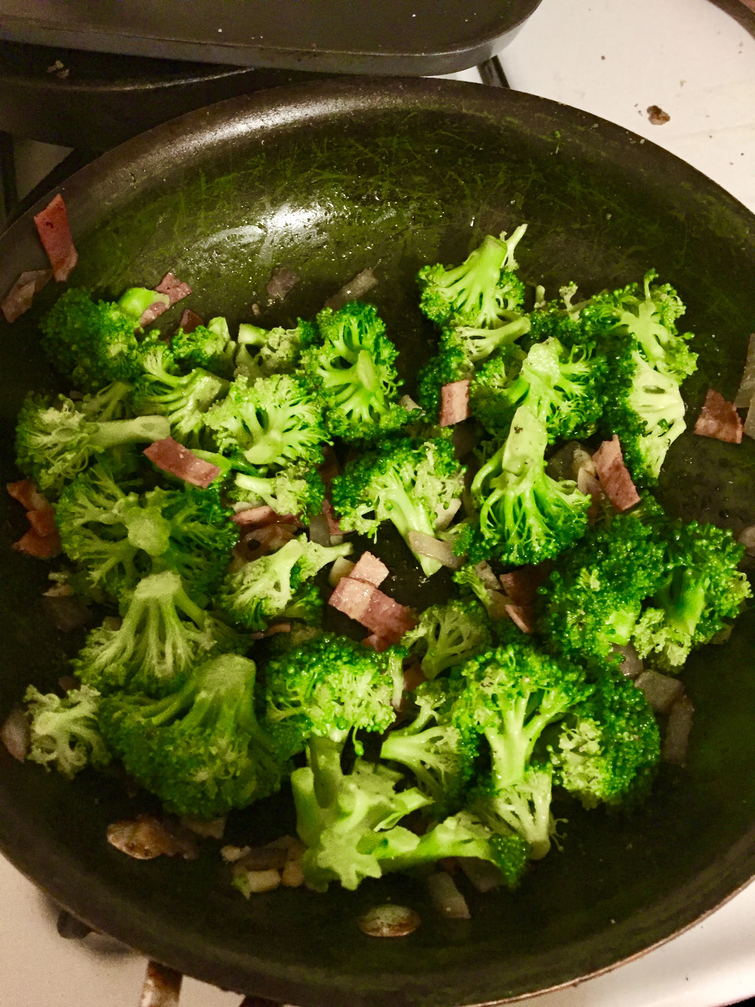 Add broccoli to the saucepan with the onions, garlic, bacon, and olive oil. Season the mixture with salt and pepper and set aside to cool. When it is cooled, add diced cheddar cheese and 3 tbls of red wine vinegar. Serve chilled and you'll elicit smiles, even if you're wearing clothes.