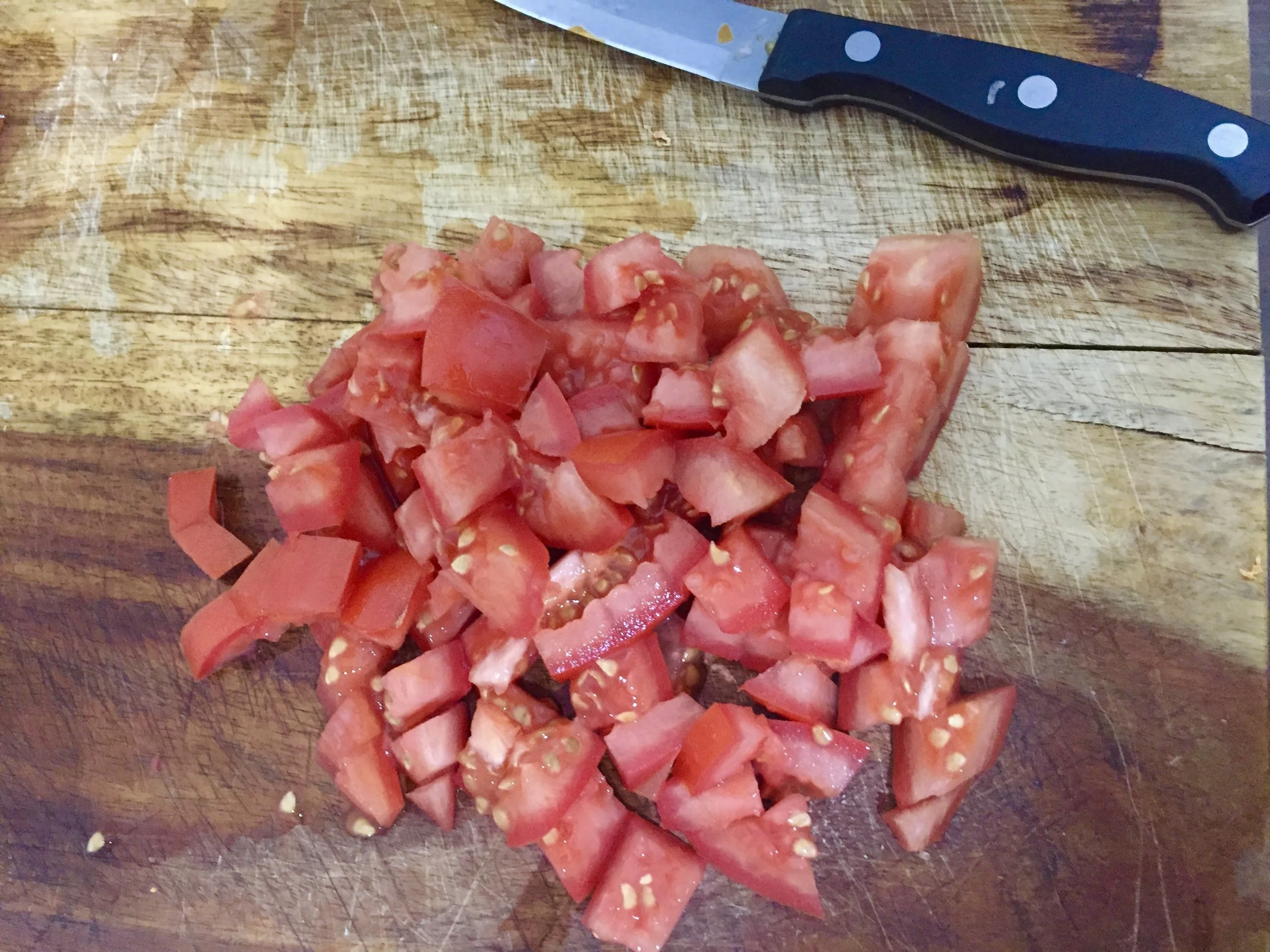 While the onions and garlic cook, dice the tomatoes. Add your tomatoes to the stockpot and cover; the point is for the tomatoes to cook down and create a base for the sausage and peppers.&nbsp;