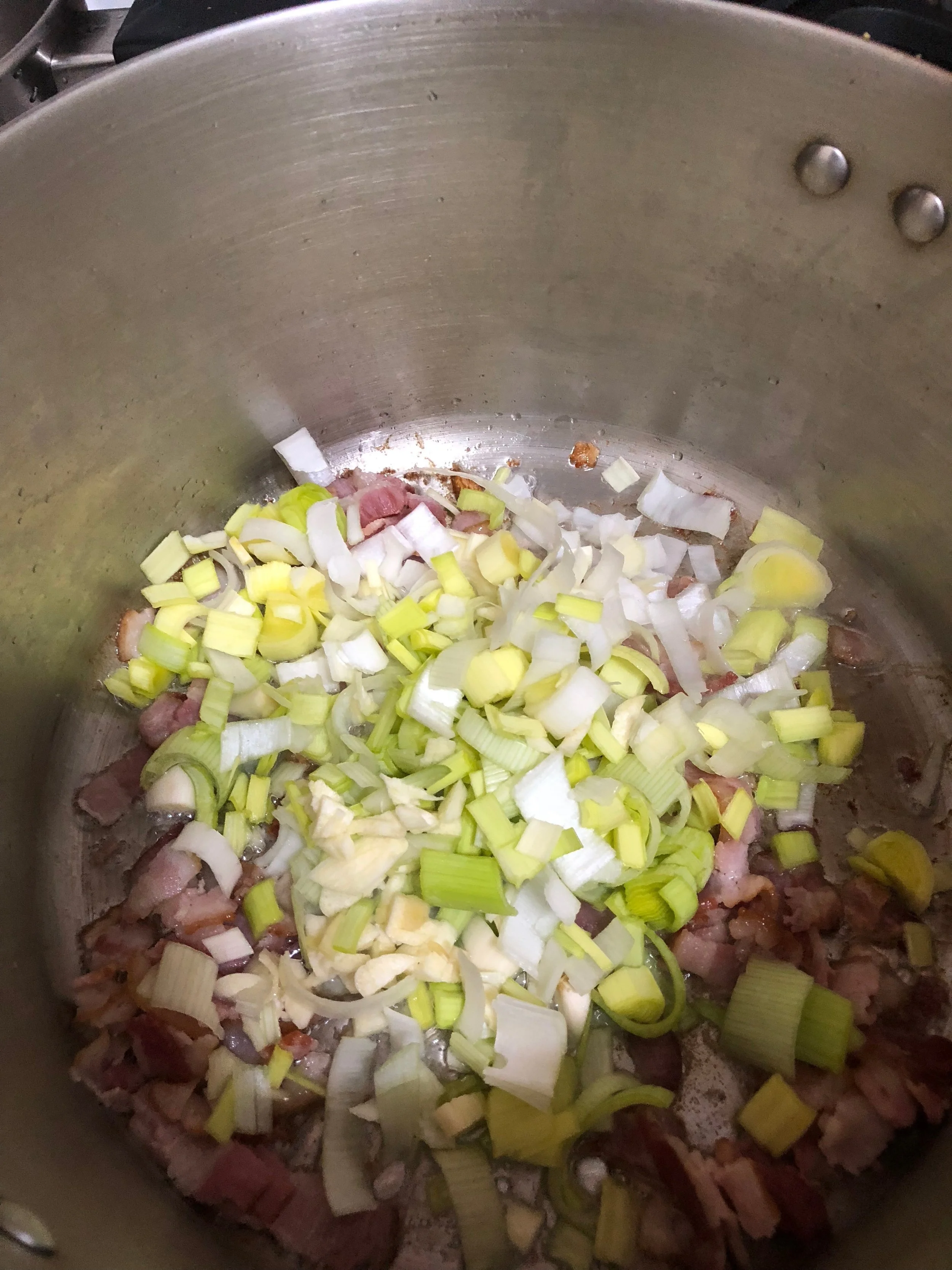 Add the garlic and leek into the stockpot with the bacon. Cook together until completely integrated and the leek pieces are clear. While they are cooking, rinse and clean the potatoes and dice them into bit sized pieces.&nbsp;