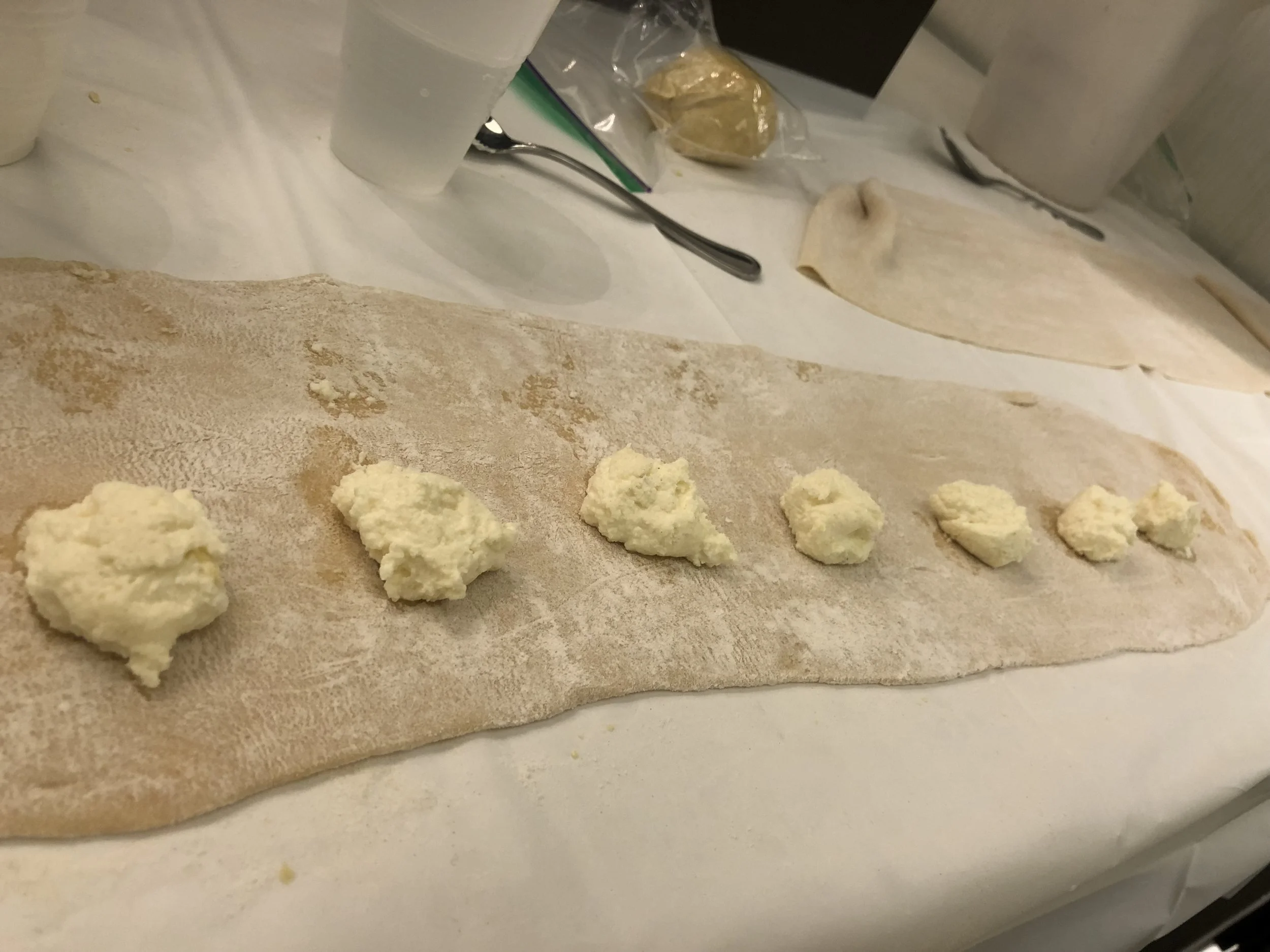Fold the dough over, so there is your own demarcated space where the filling should go. On the filling side, spoon appropriate amounts of ricotta mixture onto the sheet with foresight about how they will become ravioli. Space them so there is room f…