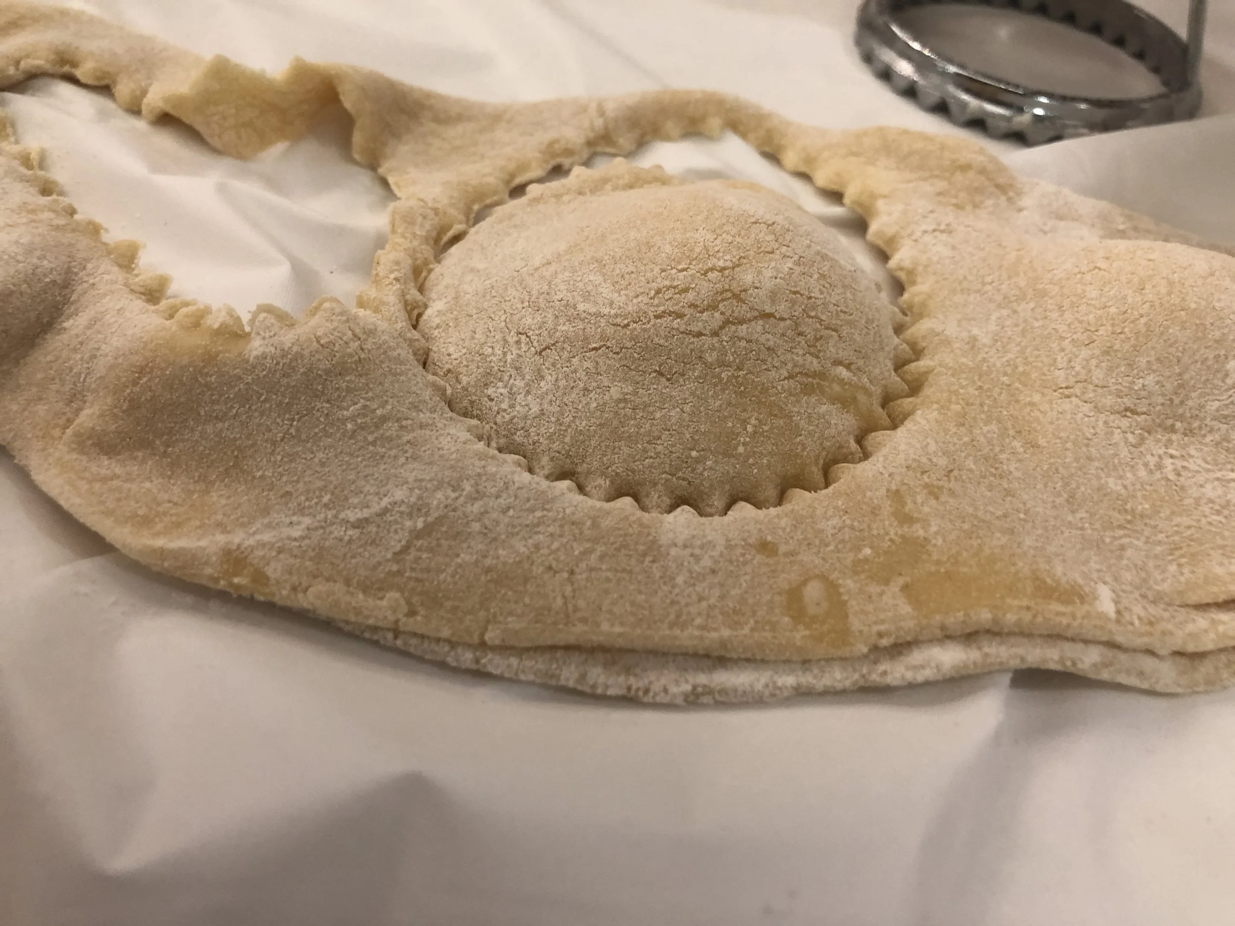 Fold the dough over so the filling make little mounds. Using your Ravioli cookie cutter, make individualized raviolis. Use your hand press around the filling of each, making individual raviolis.