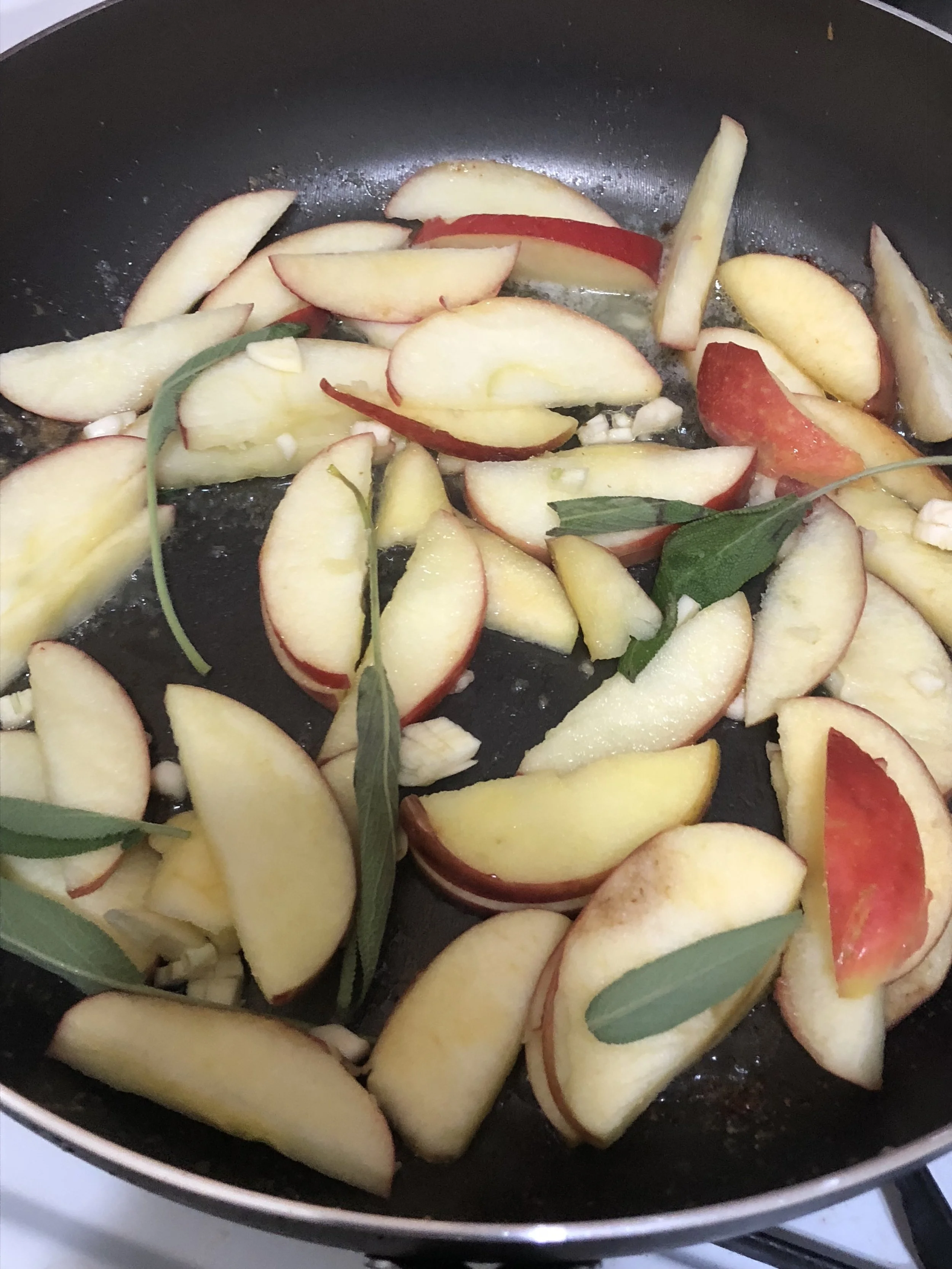 Add the apples, 6-9 sage leaves, garlic and another generous pat of butter into the skillet and cook on medium heat, stirring so both sides of the apples slices get cooked.