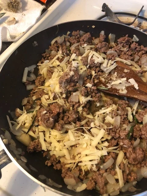 When beef is cooked through, add the onion powder, cinnamon, nutmeg, powdered garlic, salt and ground pepper. Mix throughly and taste. Add more of everything you think you should after tasting the meat. Add the shredded parmesan and the ricotta. Turn off the heat and mix throughly.